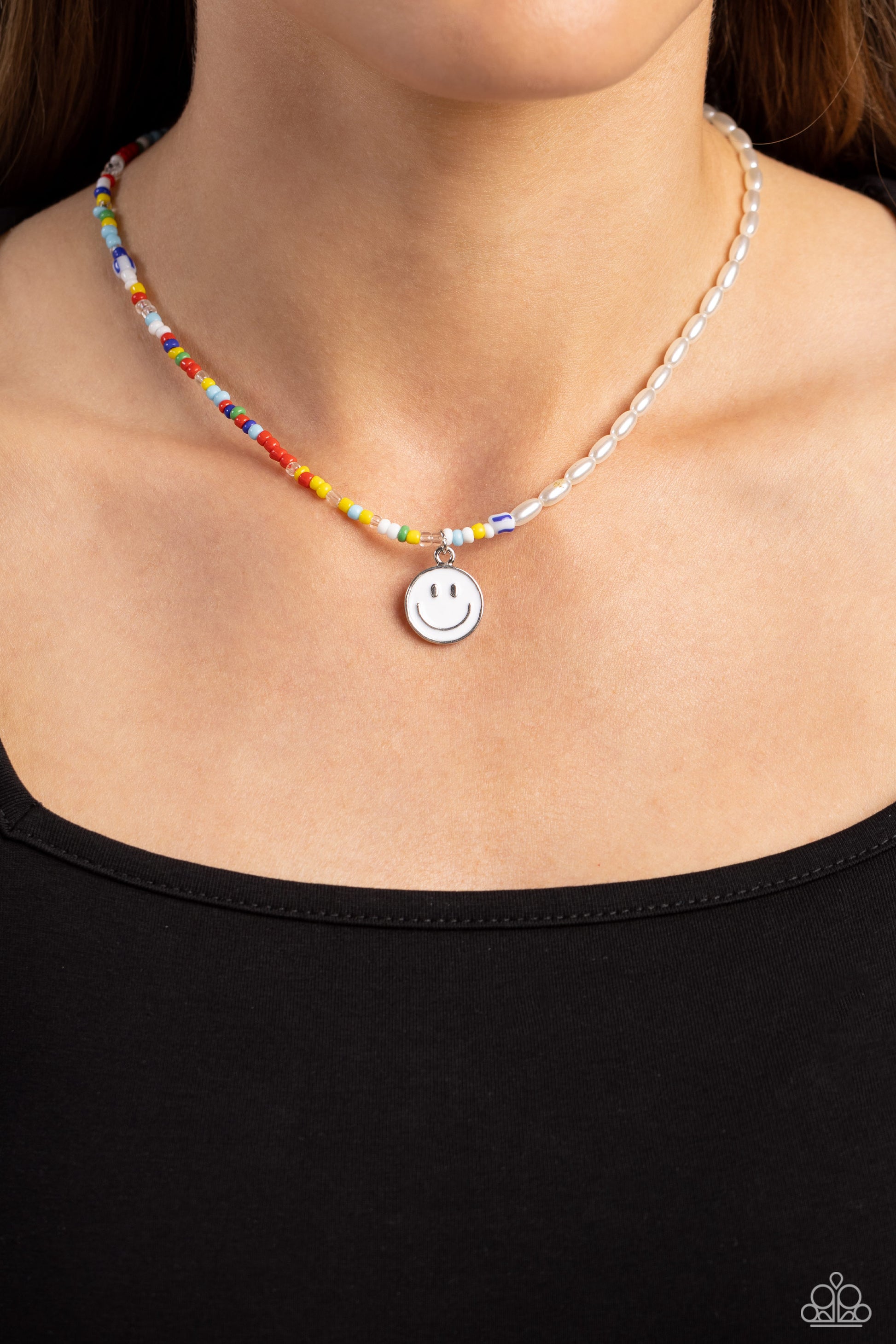 Paparazzi Accessories Smiling Showdown - White A strand of gleaming half pearl beads combines with seed beads in colorful shades for a youthful design along the collar. A white smiley face disc hangs from the colorfully classic display for additional char