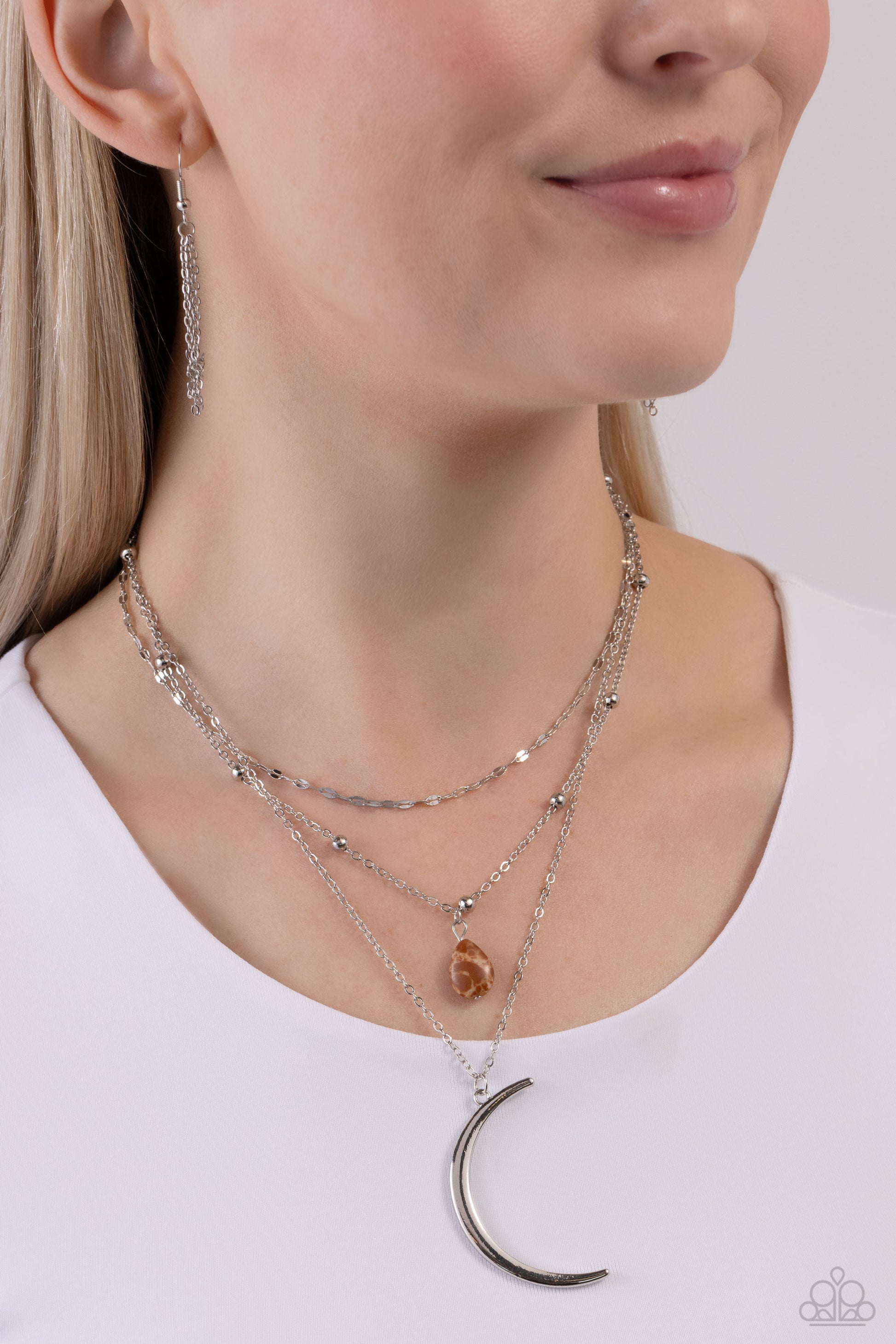 Paparazzi Accessories Lunar Landslide - Brown Three dainty silver chains delicately layer below the collar. Antiqued silver links form the uppermost chain, while a brown stone teardrop bead rests amidst silver studs on the centermost chain. A silver cresc