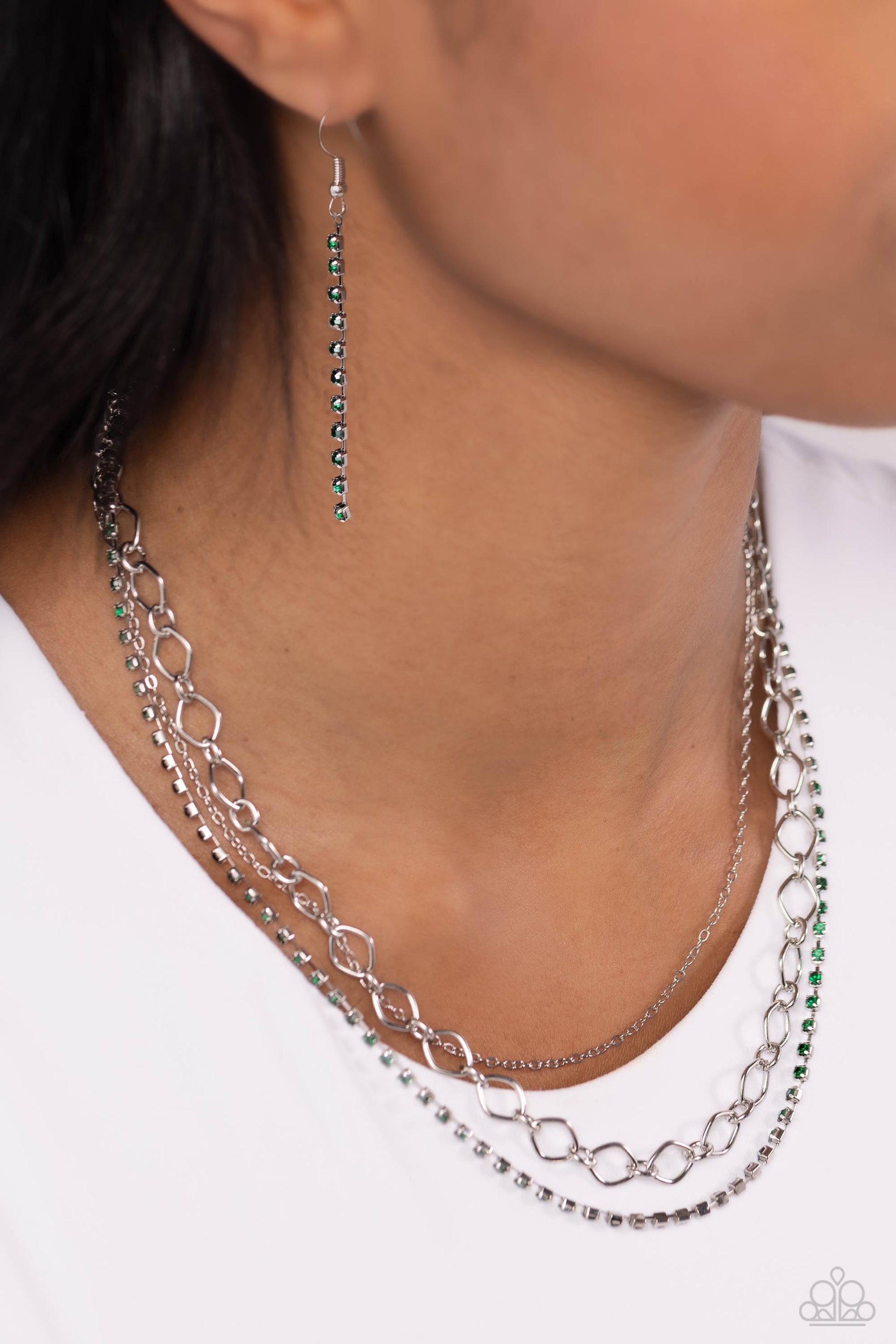 Paparazzi Accessories Tasteful Tiers - Green A dainty strand of emerald green rhinestones, set in silver square fittings, joins a dainty silver strand of silver chain and a silver oval link chain below the collar, creating refined layers. Features an adju