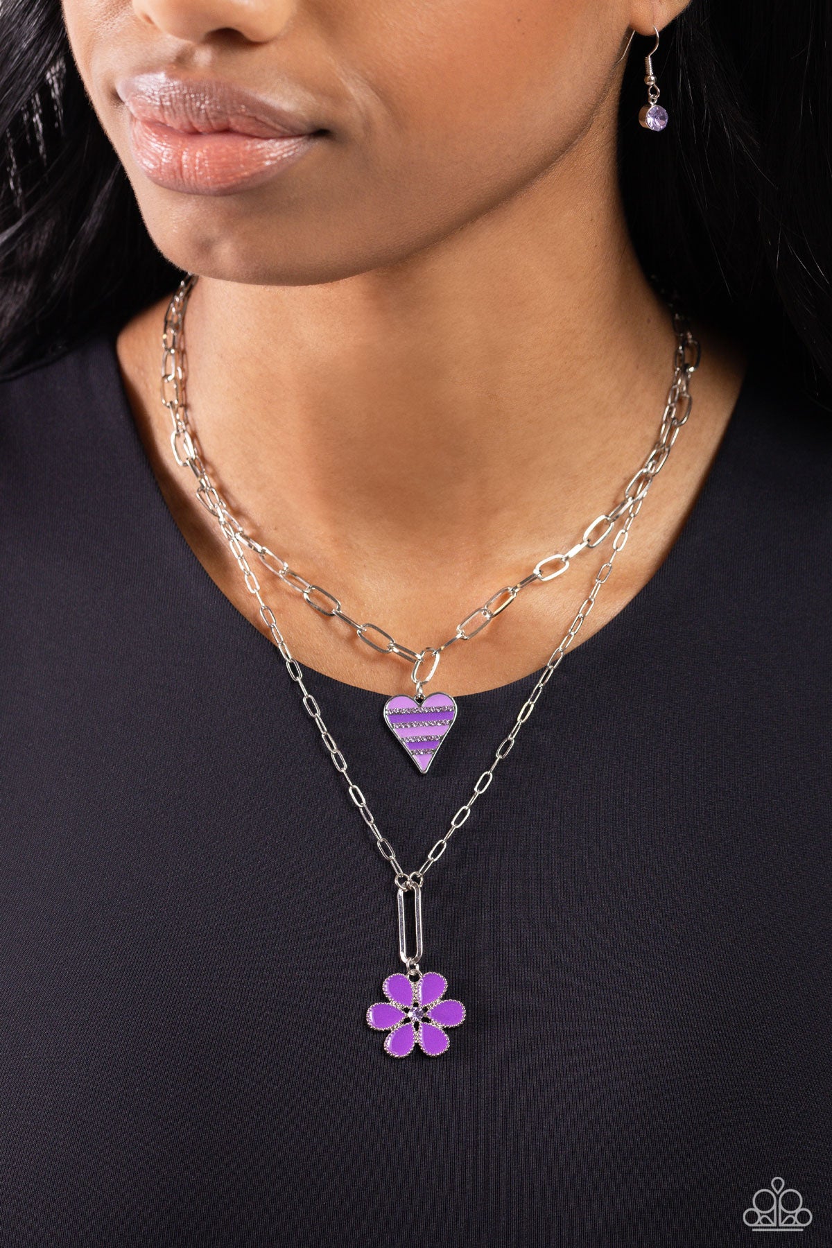 Paparazzi Accessories Childhood Charms - Purple Featuring dainty purple rhinestones, an elongated silver heart charm with stripes of lavender and purple paint, trickles along a shimmery silver paperclip link chain. A studded silver flower, with purple pet