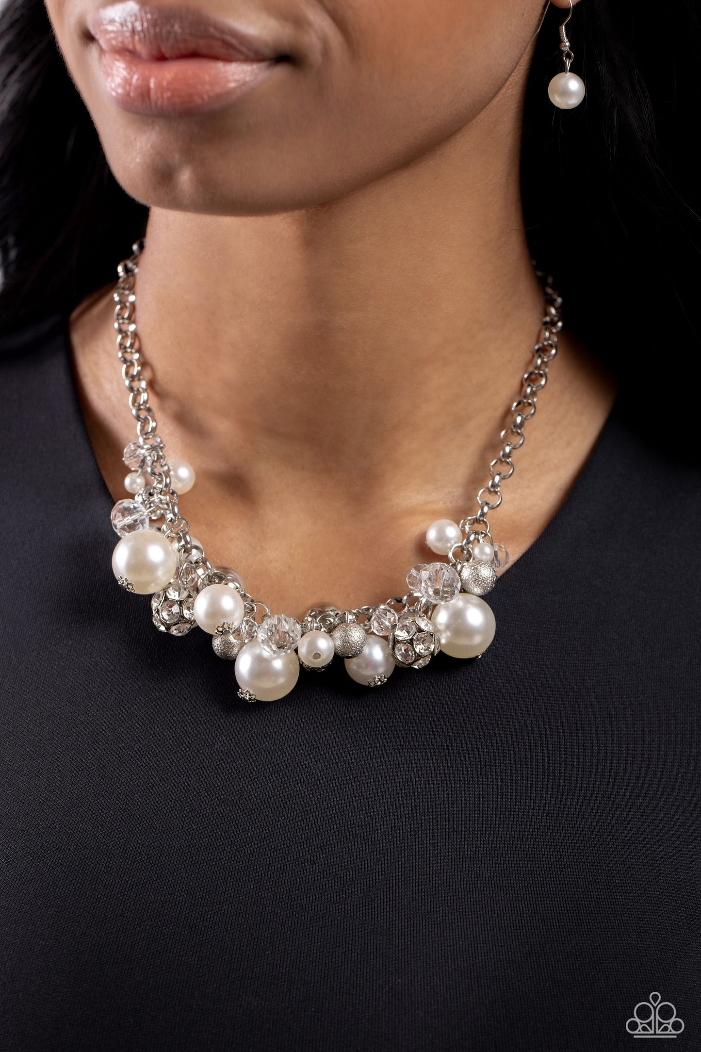 Paparazzi Accessories Corporate Catwalk - White A collection of bubbly white pearls, glittery crystal-like beads, silver beads, some embossed in shimmer, and gem-encrusted beads swing from the bottom of a chunky silver chain, creating an elegantly cluster