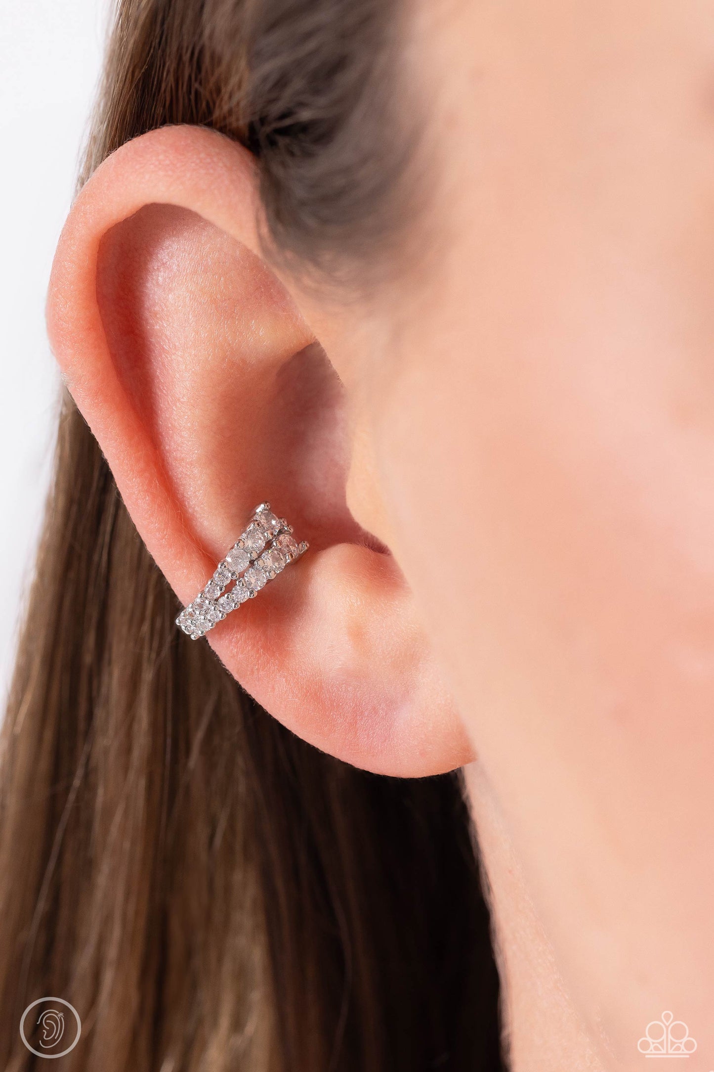 Paparazzi Accessories Pronged Parisian - White Featuring a two-pronged fitting, white rhinestones with a light iridescent sheen gradually decrease in size to create a blinding, adjustable, one-size-fits-all cuff. Sold as one pair of cuff earrings. Jewelry