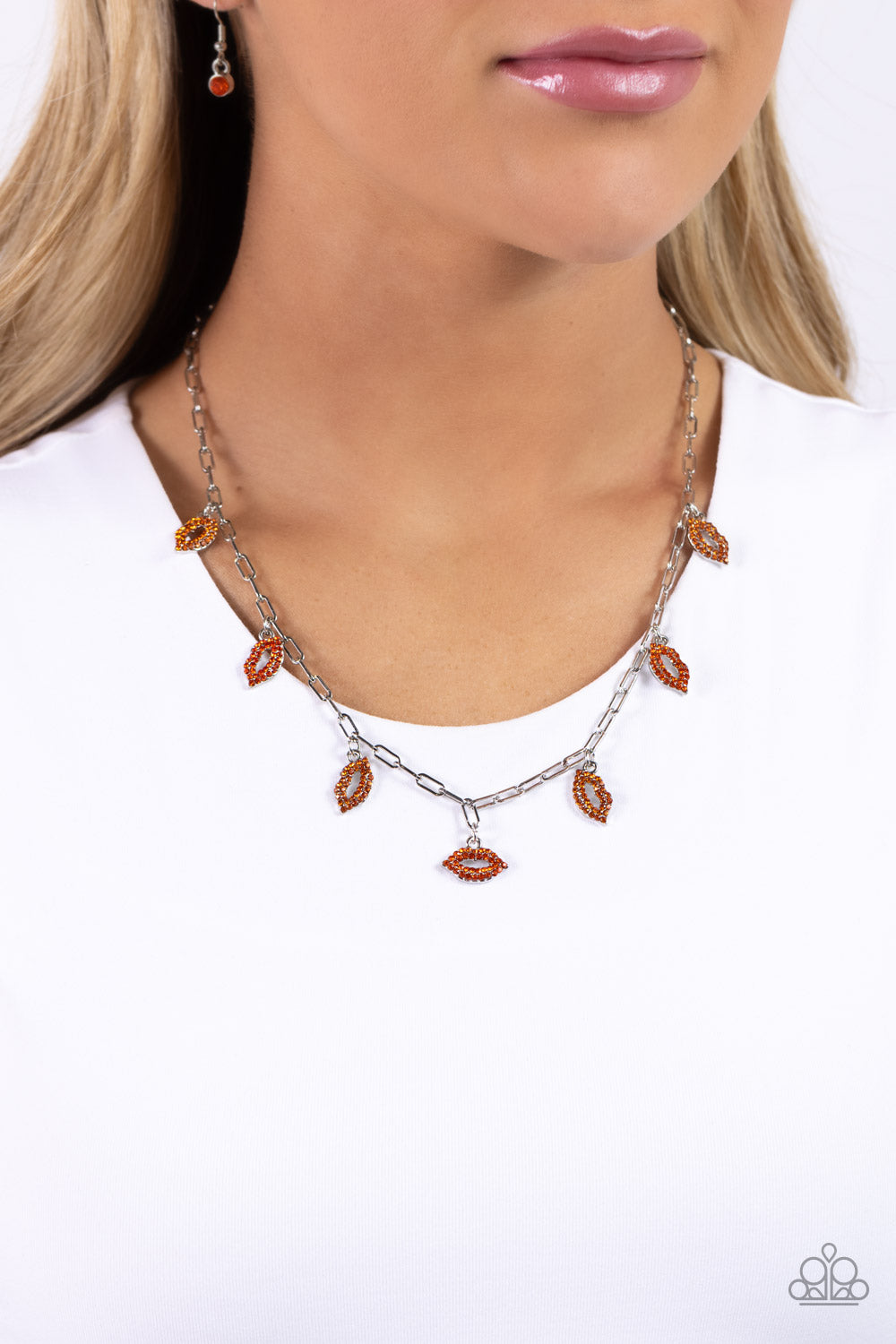 Paparazzi Accessories KISS the Mark - Orange Gliding along a silver paperclip chain, a pouty collection of lip charms, each embossed in various shades of orange rhinestones, alternates below the collar for a love-struck fashion. Features an adjustable cla