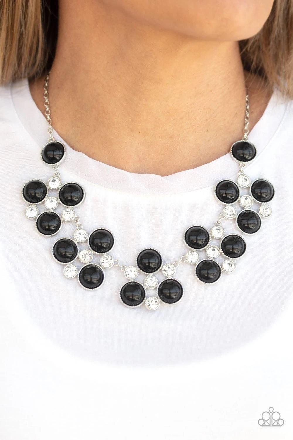 Paparazzi Accessories Night At The Symphony - Black Sleek silver frames adorned in a refined mix of oversized black beads and glassy white rhinestones, delicately link below the collar for a dramatically glamorous look. Features an adjustable clasp closur