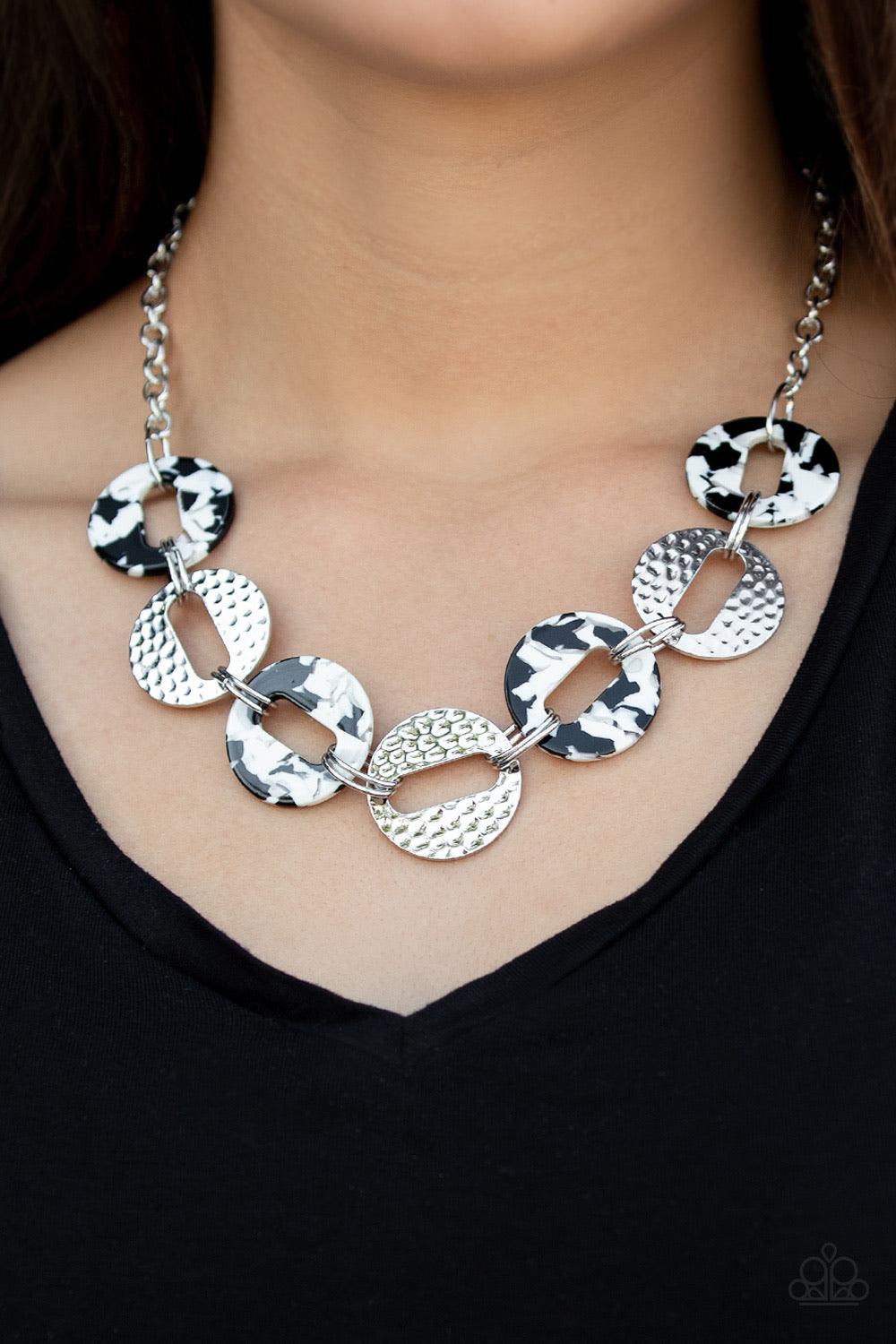 Paparazzi Accessories Retro Retrograde - White Featuring airy circular shapes, hammered silver frames link with speckled black and white acrylic frames below the collar for a colorfully retro look. Features an adjustable clasp closure. Sold as one individ