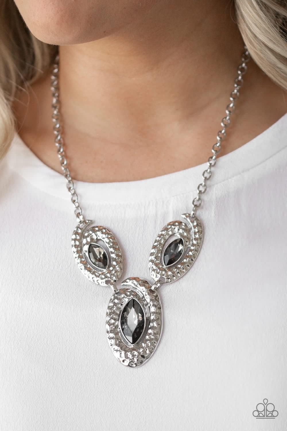 Paparazzi Accessories Metro Mystique - Silver A trio of smoky marquise-cut rhinestones are nestled inside swirls of hammered silver frames, creating a dazzling statement piece below the collar. Features an adjustable clasp closure. Jewelry