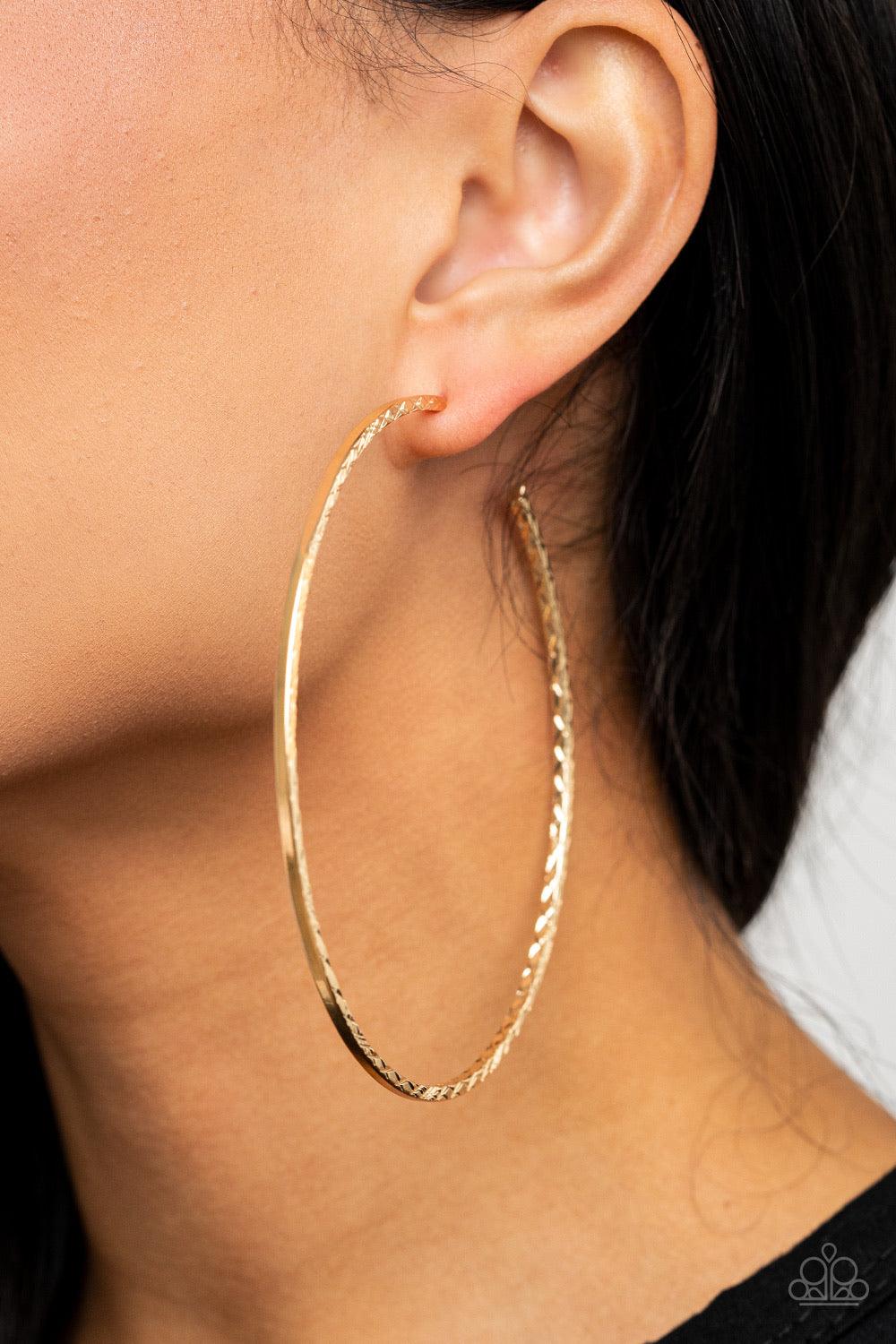 Paparazzi Accessories Diamondback Diva - Gold Etched in a diamond cut textures, a dramatically oversized shiny gold hoop curls around the ear for an exaggerated look. Earring attaches to a standard post fitting. Hoop measures approximately 3 1/2" in diame
