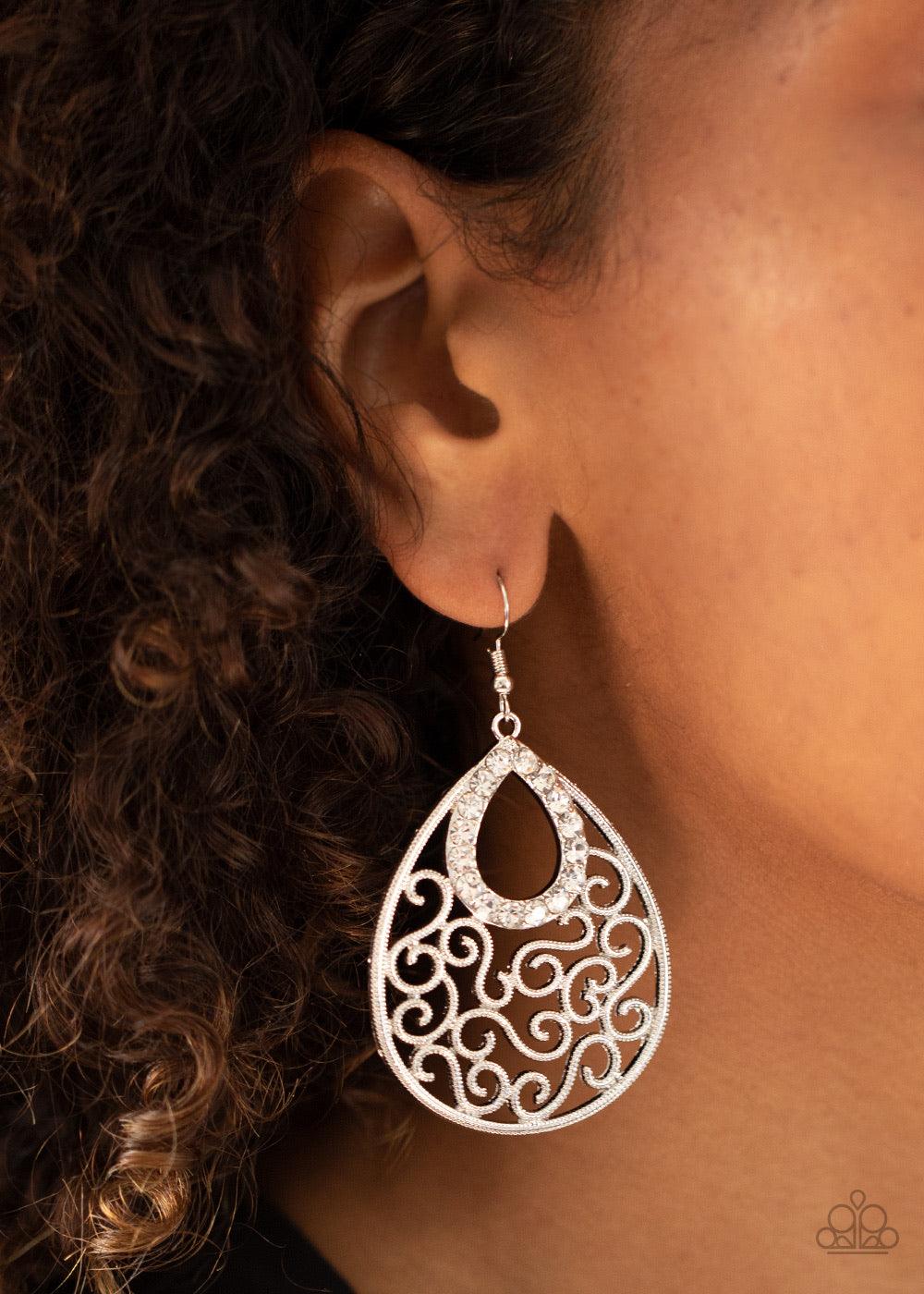Paparazzi Accessories Seize The Stage - White A glittery white rhinestone teardrop frame nestles at the top of an antiqued silver teardrop filled with whimsical vine-like filigree. Earring attaches to a standard fishhook fitting. Sold as one pair of earri