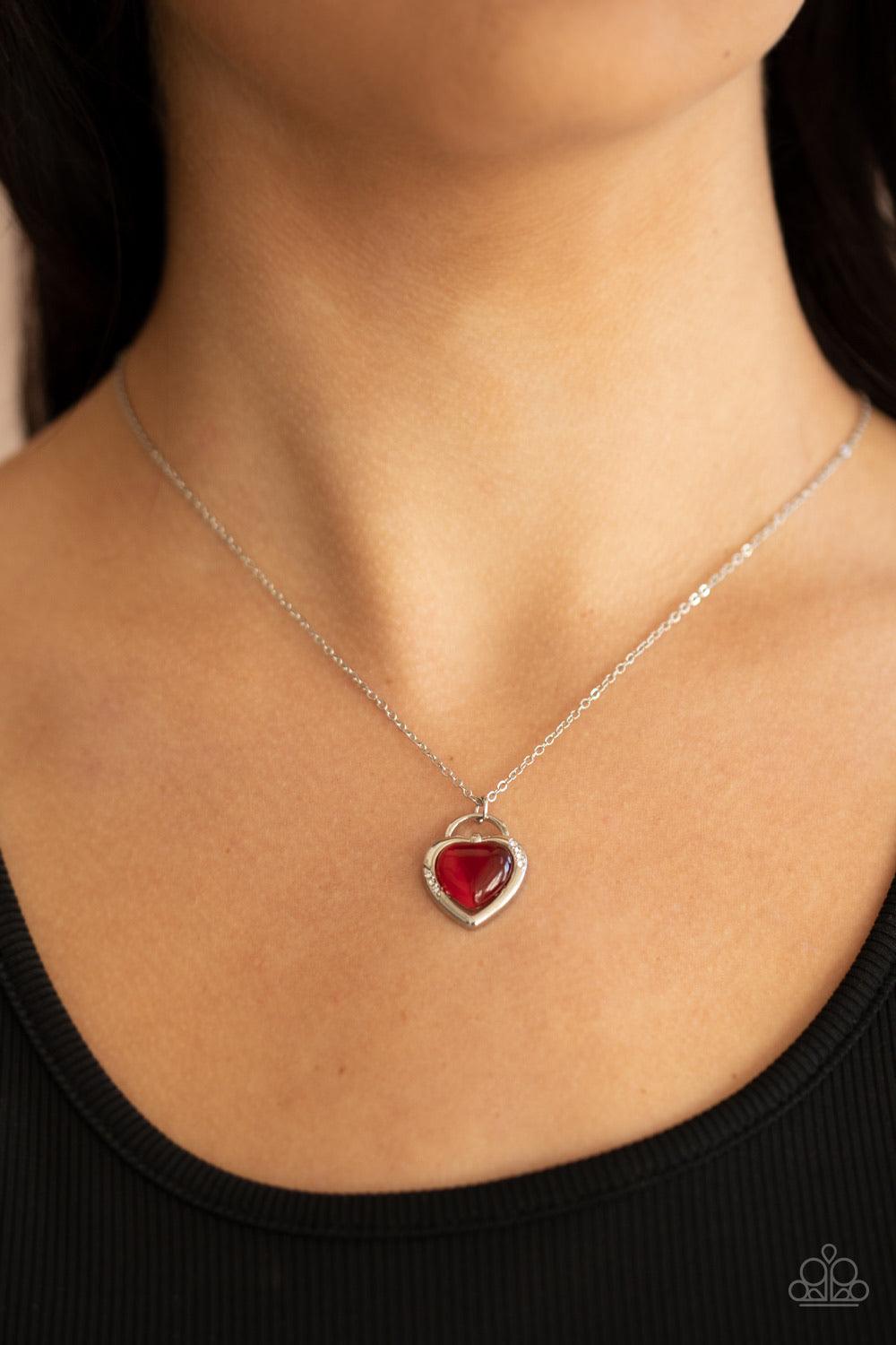 Paparazzi Accessories A Dream Is A Wish Your Heart Makes - Red Featuring a red cat's eye stone center, a glistening silver locket inspired frame glides along a dainty silver chain below the collar for a charming look. Sections of dainty white rhinestones