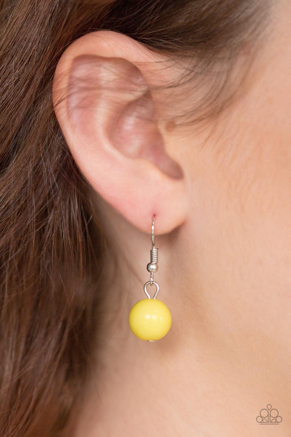 Paparazzi Accessories Brazilian Bay - Yellow Featuring glassy and polished finishes, round and asymmetrical yellow beads trickle from the bottom of a double-linked silver chain. An additional silver chain is layered above the summery beading for a seasona