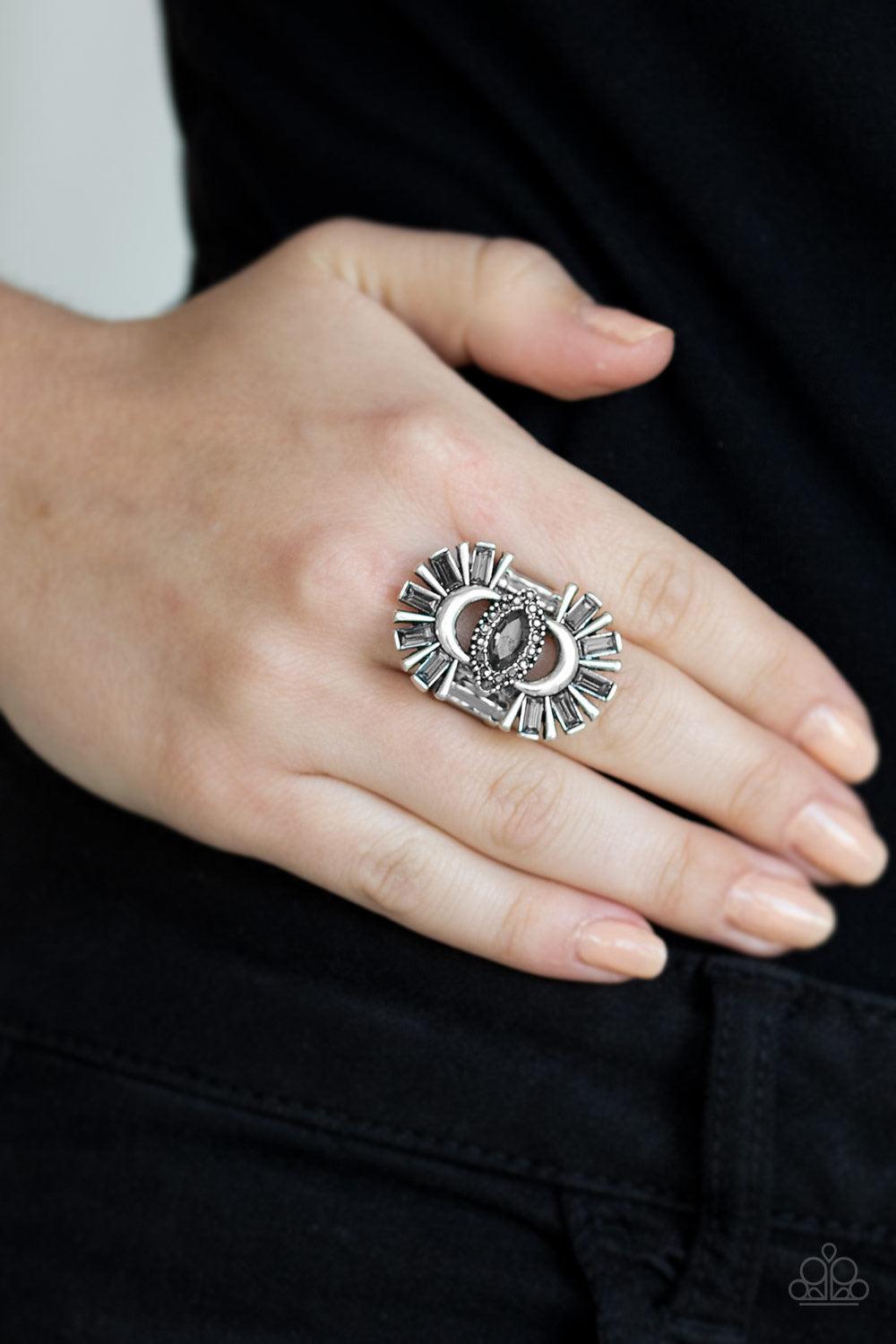 Paparazzi Accessories Deco Diva - Silver A collision of smoky emerald-cut rhinestones and antiqued silver frames flare from the top and bottom of a smoky rhinestone encrusted center, creating a dramatic centerpiece atop the finger. Features a stretchy ban