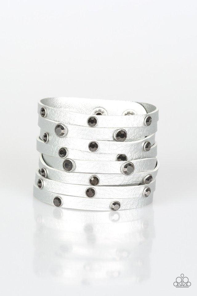 Paparazzi Accessories Go-Getter Glamorous - Silver Brushed in a metallic shimmer, a thick gray leather band has been spliced into eight strips across the wrist. Encased in sleek silver fittings, glittery hematite rhinestones are sprinkled across the cente