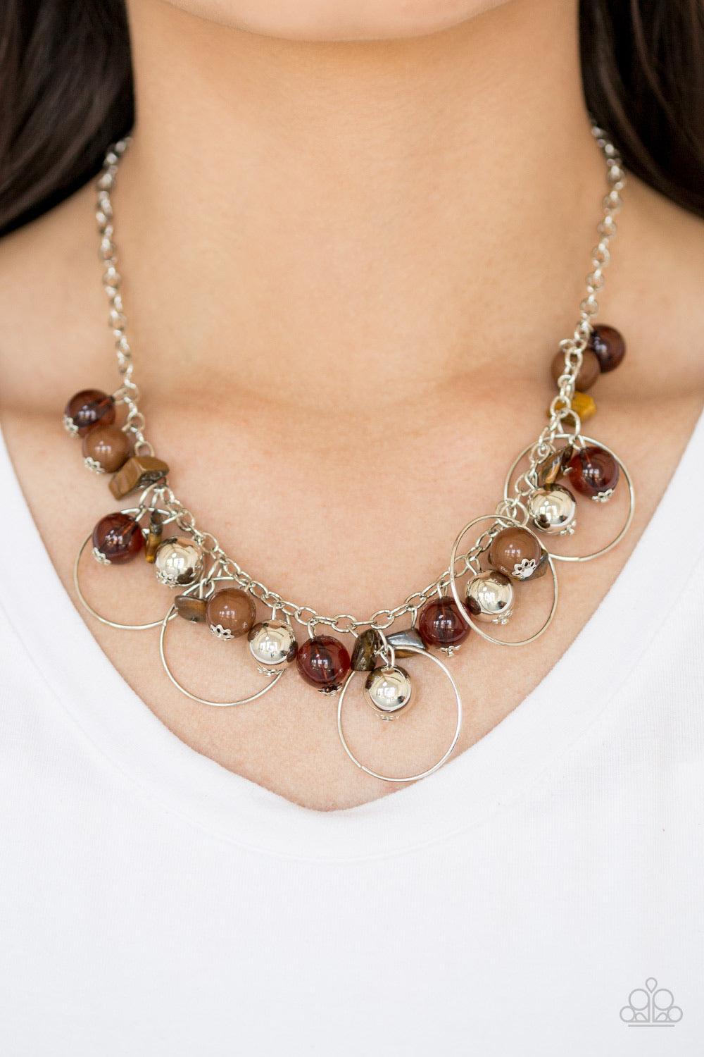 Paparazzi Accessories Mountain Mosaic - Brown Glassy brown, polished brown, and classic silver chains swing from the bottom of a shimmery silver chain. Infused with large silver hoops, bits of tranquil brown rock beading trickle between the beaded accent,