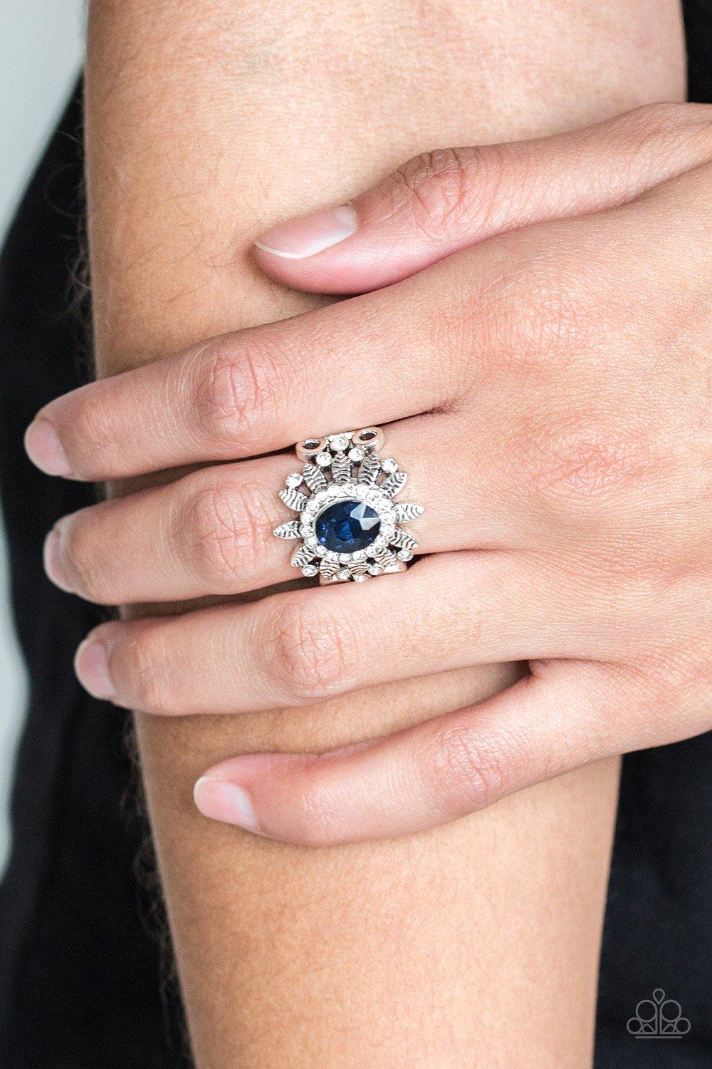 Paparazzi Accessories Burn Bright - Blue Ringed in glittery white rhinestones, a glittery blue gem is pressed into the center of a leafy silver frame. Dainty white rhinestones are sprinkled along the shimmery foliage for a refined finish. Features a stret