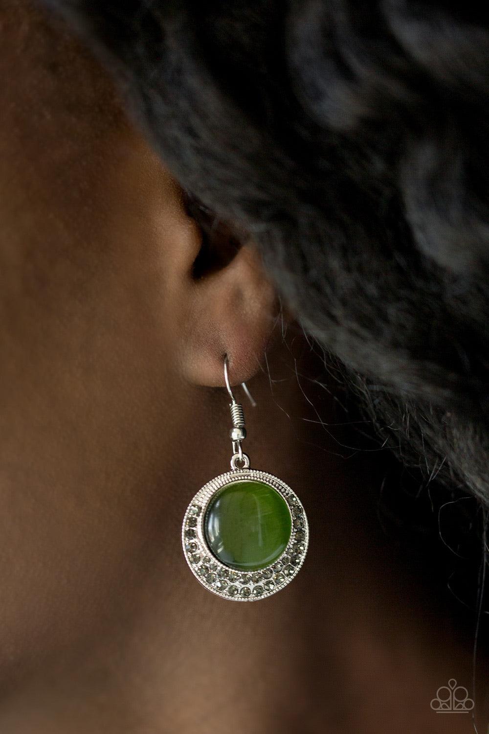 Paparazzi Accessories Gleam Away - Green As if dipped in glitter, the bottom of a silver frame is encrusted in smoky rhinestones. A glowing green moonstone is pressed into the center of the frame for a whimsical finish. Earring attaches to a standard fish