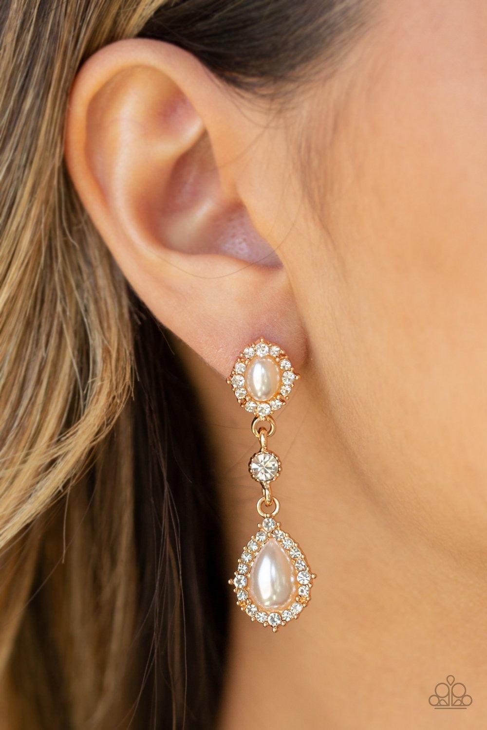 Paparazzi Accessories All-GLOWING - Gold A solitaire white rhinestone is linked between two pearly and white rhinestone encrusted frames, creating an elegant lure. Earring attaches to a standard post fitting. Jewelry