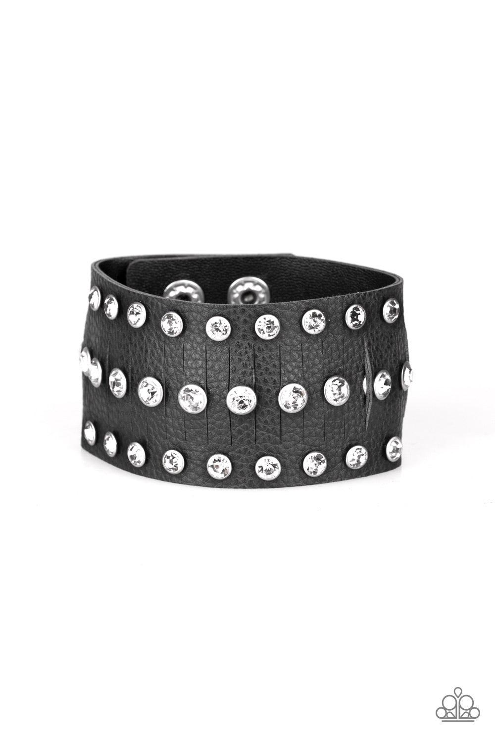 Paparazzi Accessories Now Taking The Stage - Black Pressed into sleek silver frames, glittery white rhinestones are studded across a thick black leather band featuring a center lined with slits for a sassy finish. Features an adjustable snap closure. Sold