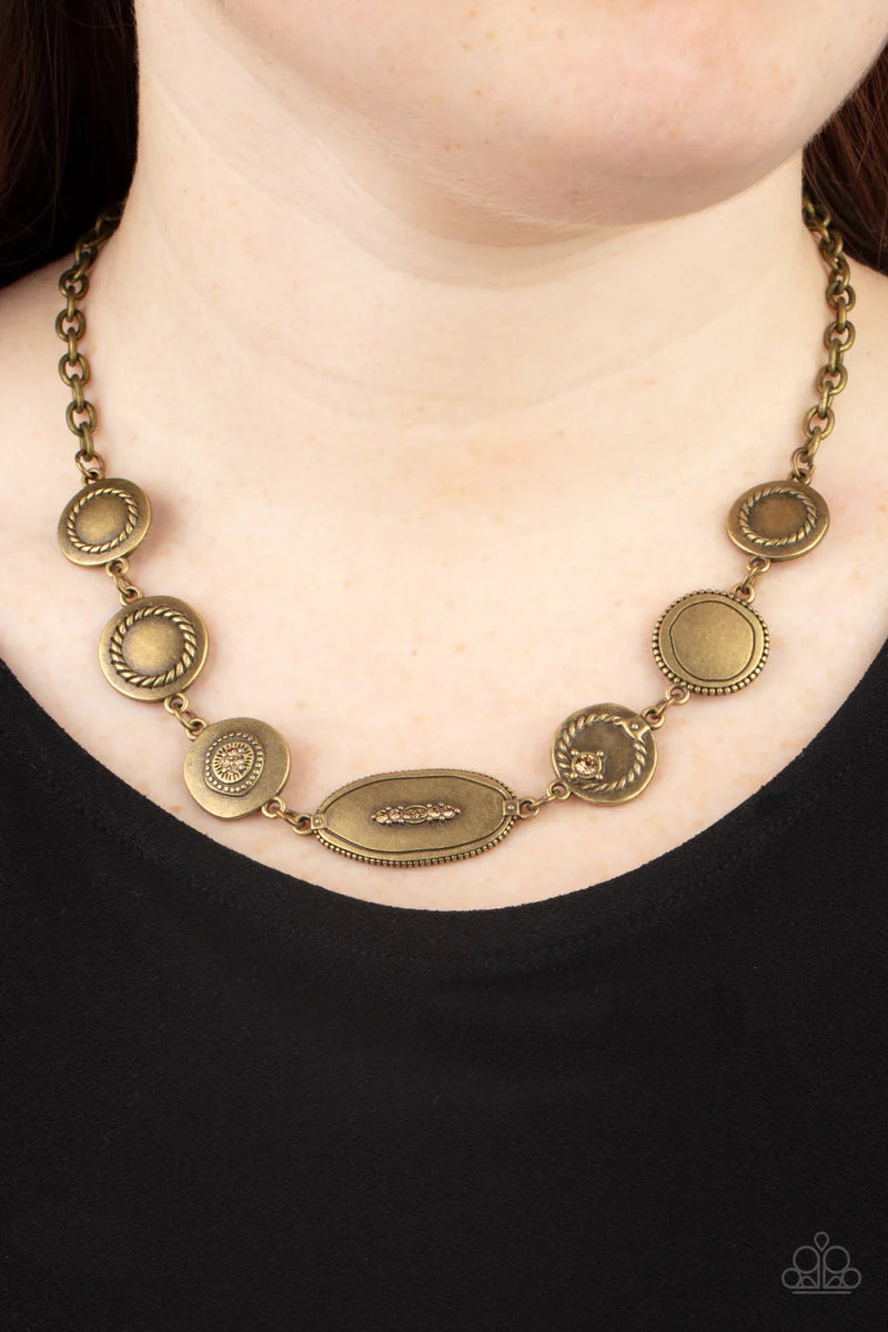 Paparazzi Accessories Uniquely Unconventional - Brass Sporadically dotted in dainty topaz rhinestones and metallic rope-like texture, an asymmetrical assortment of rustic brass frames delicately link below the collar for a one-of-a-kind shimmer. Features