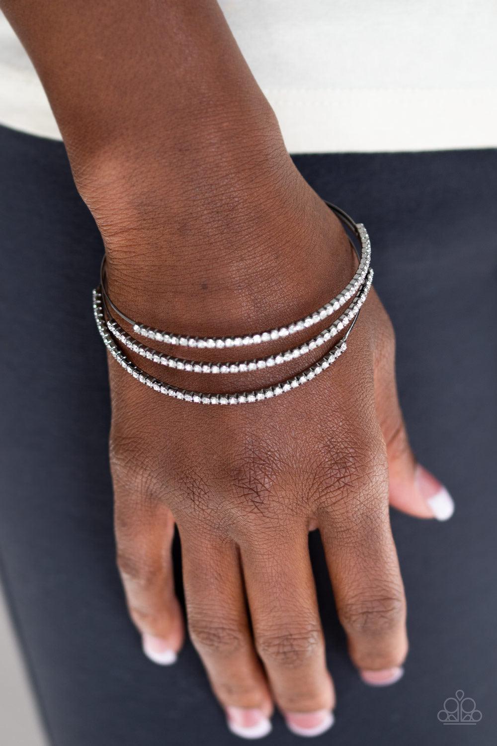 Paparazzi Accessories Iridescently Infatuated - Black Sections of glittery white rhinestones are encrusted along the tops of three dainty gunmetal bars that coalesce into a glitzy cuff around the wrist. Jewelry