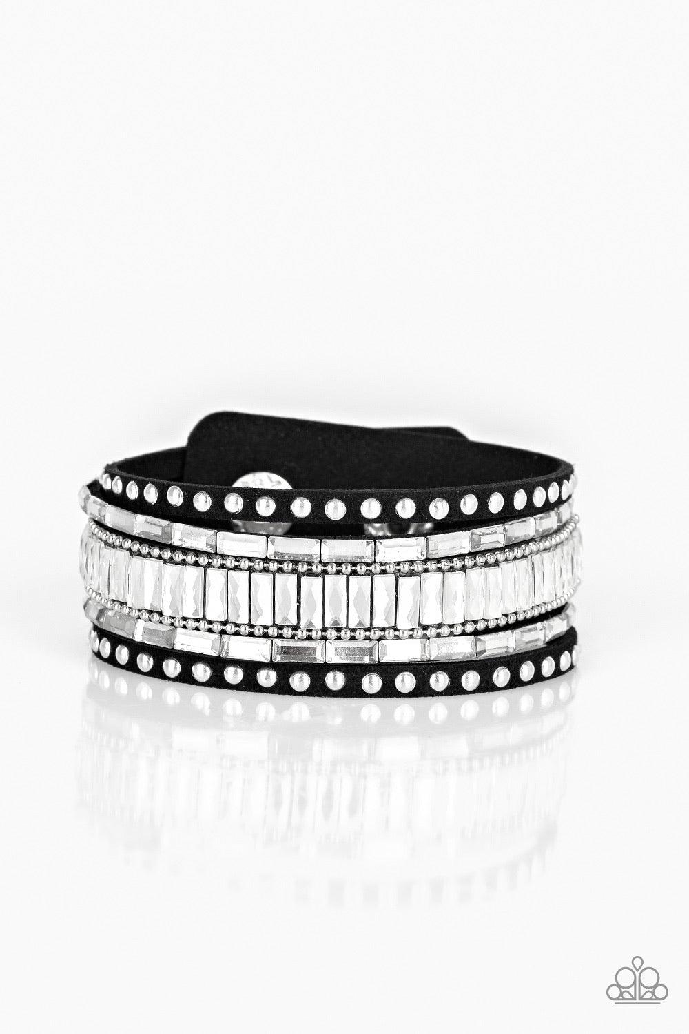 Paparazzi Accessories Rock Star Rocker - Black Shiny silver studs, dainty silver ball chains, and edgy white emerald-cut rhinestones race along a spliced black suede band for a rock star look. Features an adjustable snap closure. Sold as one individual br