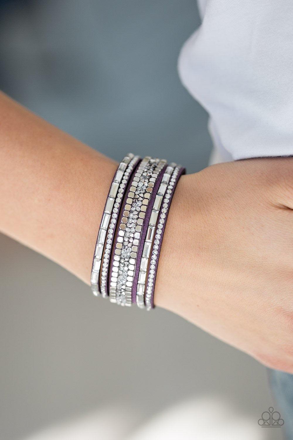 Paparazzi Accessories Rebel In Rhinestones - Purple Featuring round and emerald style cuts, glassy white rhinestones join flat silver cubes and metallic prism rhinestones along a purple suede band for a sassy look. Features an adjustable snap closure. Jew