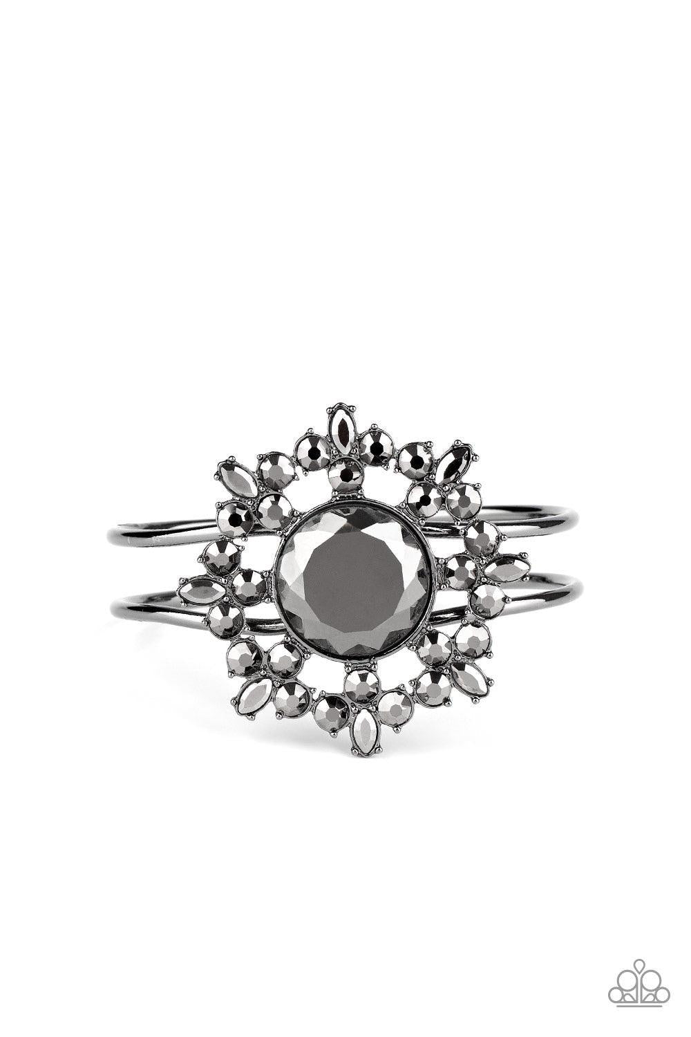 Paparazzi Accessories Elaborate Elegance - Black Glittery hematite petals bloom from an oversized hematite rhinestone center, creating a dazzling floral centerpiece atop an airy gunmetal cuff. Features a hinged closure. Sold as one individual bracelet. Je