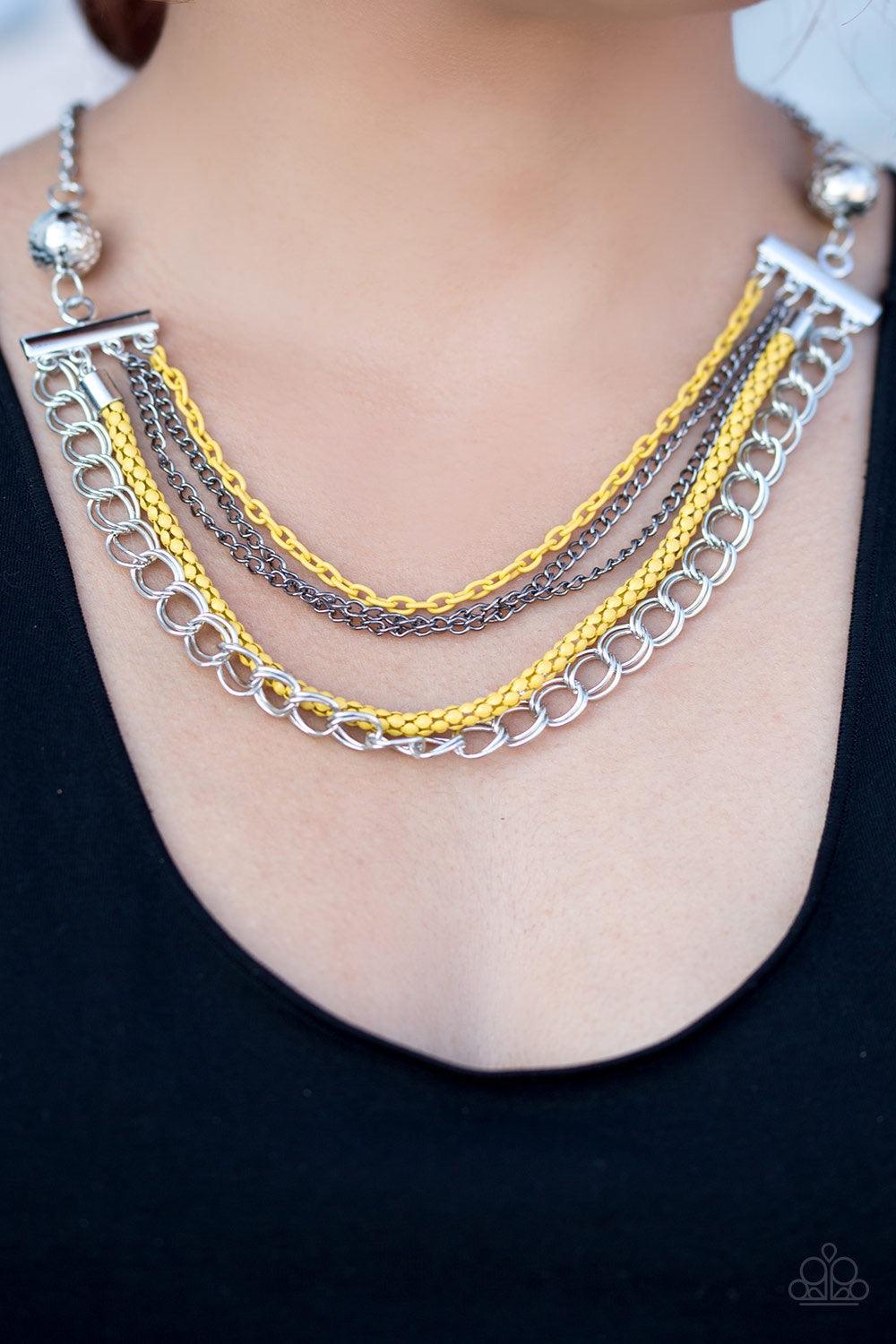 Paparazzi Accessories High-Intensity - Yellow Two floral silver beads give way to an array of yellow, gunmetal, and silver chains. Strung between two metal beads, the mismatched chains layer below the collar in a colorfully industrial fashion. Features an