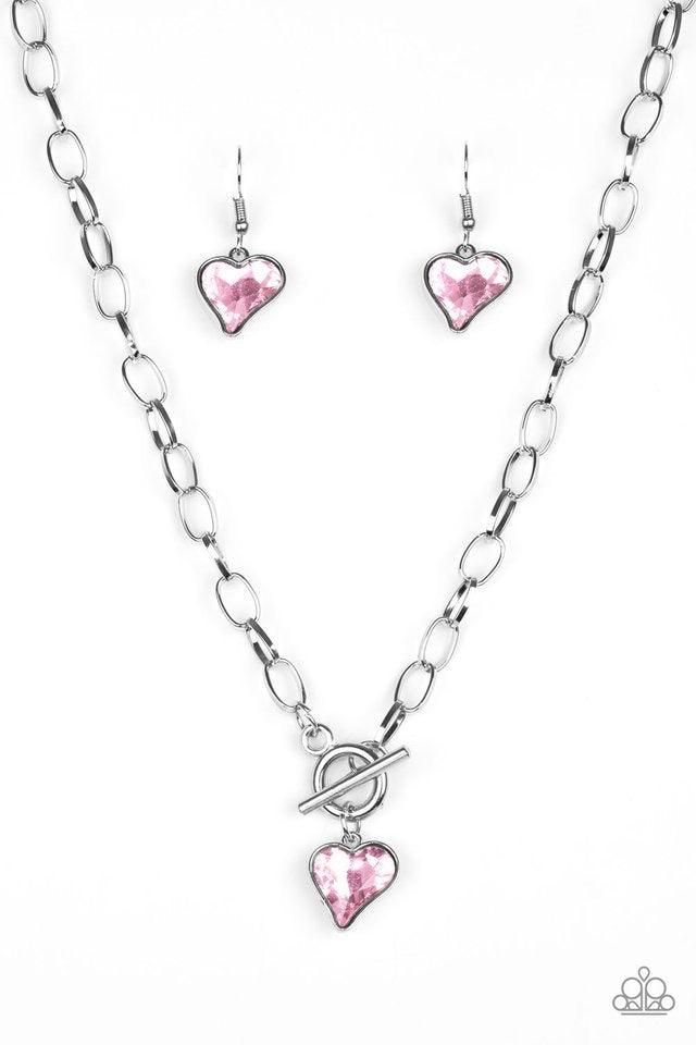 Paparazzi Accessories Princeton Princess - Pink Cut into a whimsical heart shape, a glittery pink gem swings from the bottom of a glistening silver chain below the collar for a charming look. Features a toggle closure. Jewelry