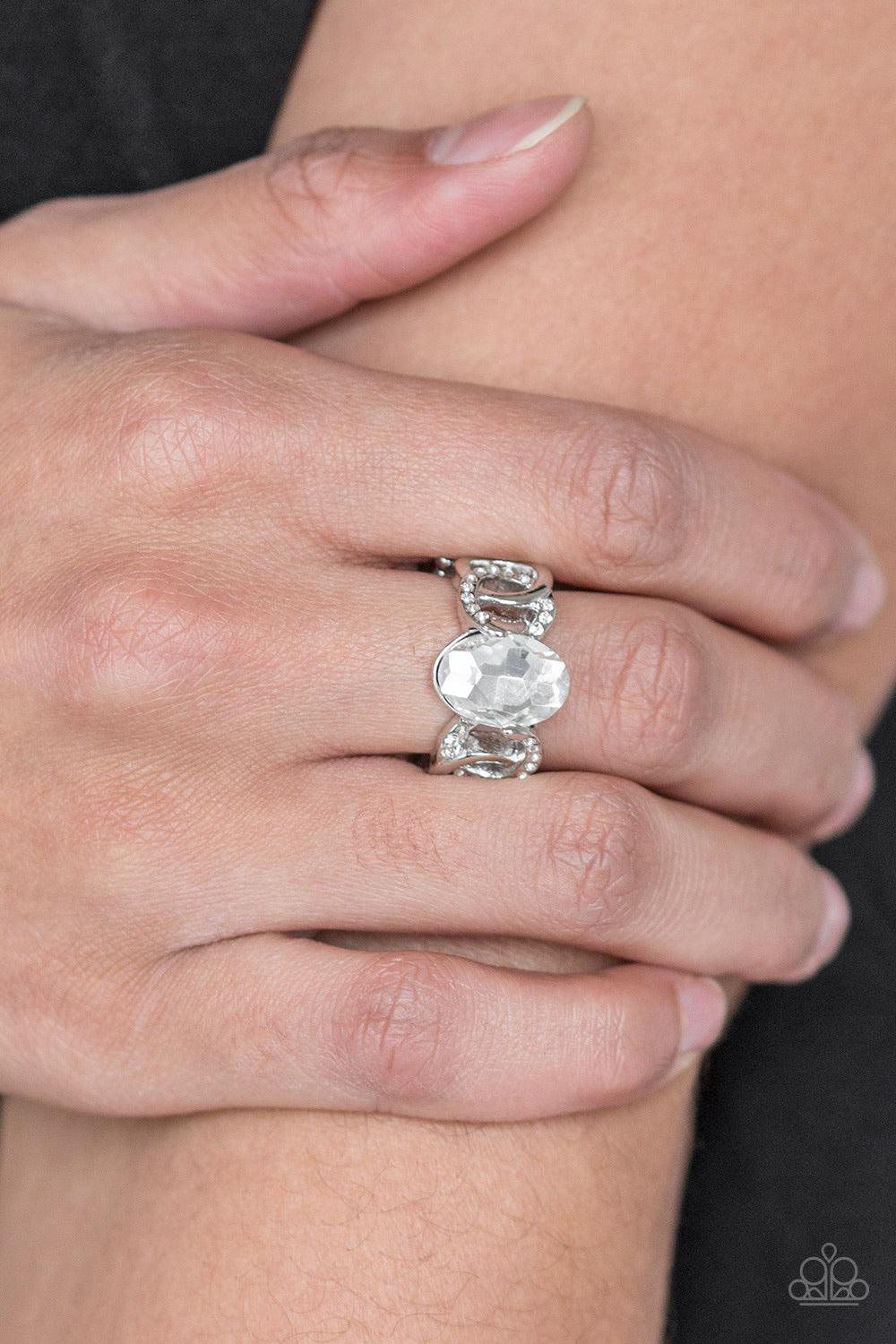 Paparazzi Accessories Supreme Bling - White White rhinestone encrusted frames and shiny silver frames link across the finger, coalescing into an airy band. A glittery white rhinestone is pressed into the center of the band for a glamorous finish. Features
