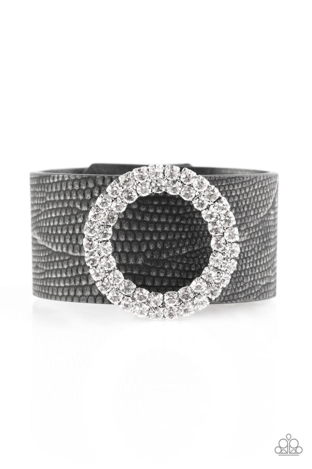Paparazzi Accessories Ring In The Bling - Black Encrusted in glittery white rhinestones, a round frame slides along a rustic strip of black leather for a fierce look. Features an adjustable snap closure. Jewelry