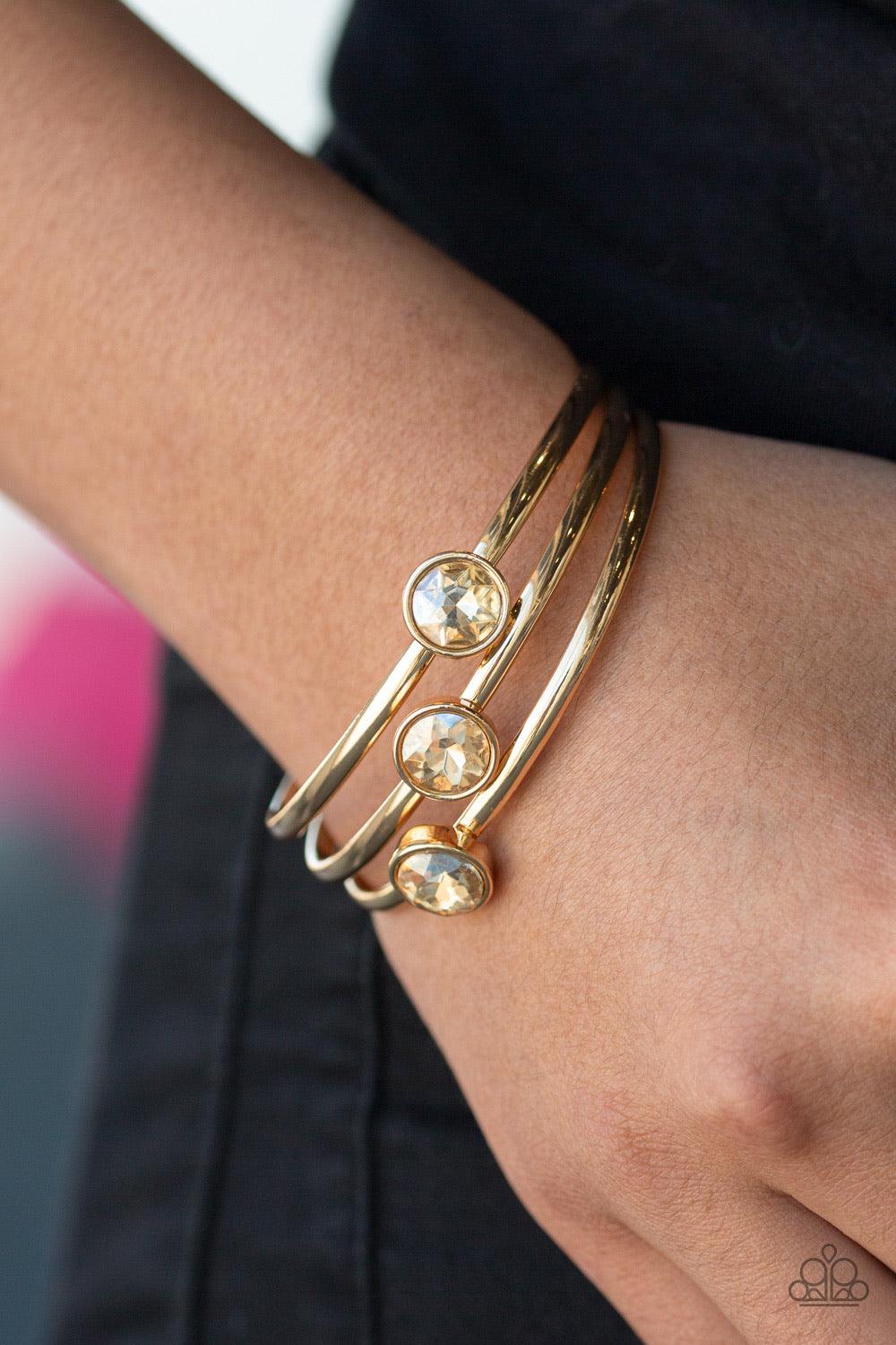 Paparazzi Accessories Be All You Can BEDAZZLE - Gold Encased in sleek gold frames, dazzling golden gems sit atop thick gold bangles for a refined flair. Jewelry