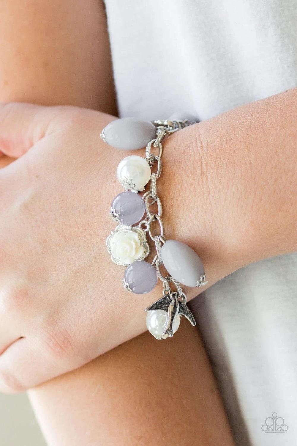 Paparazzi Accessories Love Doves - Silver Gorgeous pearls, luminescent gray beading, and a collection of shiny silver charms, including a bird and a feather, dance around the wrist in a whimsical fashion. Features an adjustable clasp closure. Sold as one