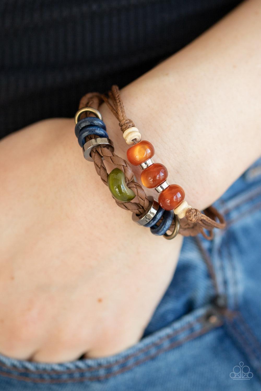 Paparazzi Accessories Uncharted Territory ~Brown A colorful collection of glassy, wooden, and metallic beads are threaded along strands of shiny twine and braided leather cording for an urban flair. Features an adjustable sliding knot closure.