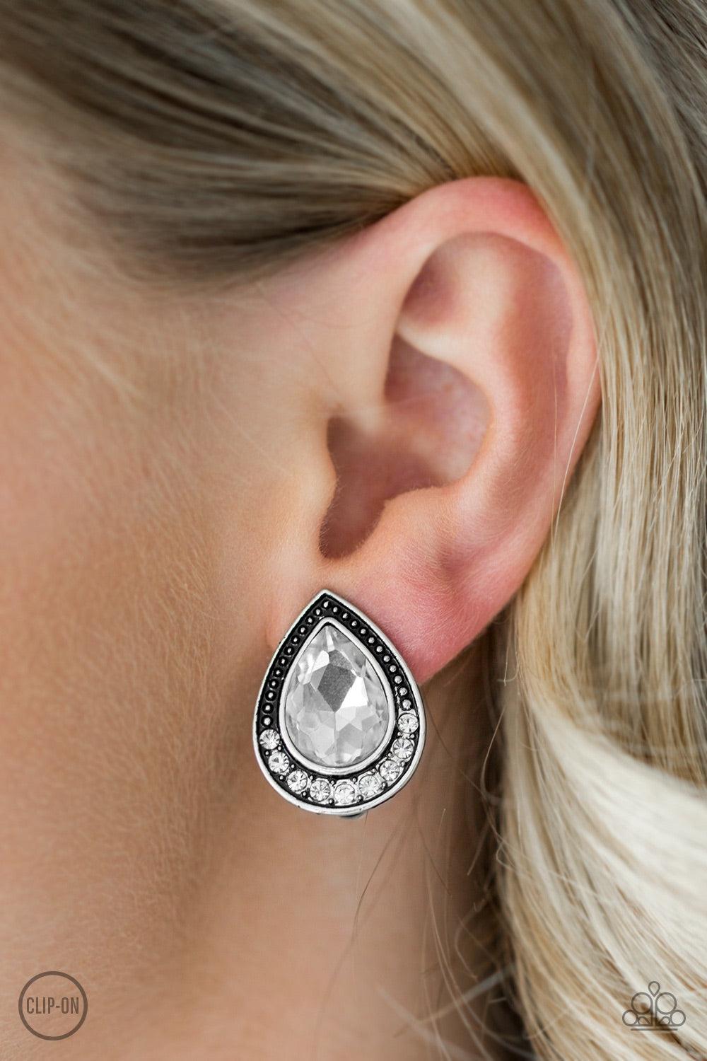 Paparazzi Accessories Radiantly Ravishing - White *Clip-On A glassy white gem is pressed into an ornate silver teardrop. Infused with dainty silver studs, the bottom of the frame is encrusted in glittery white rhinestones for a classic finish. Earring att