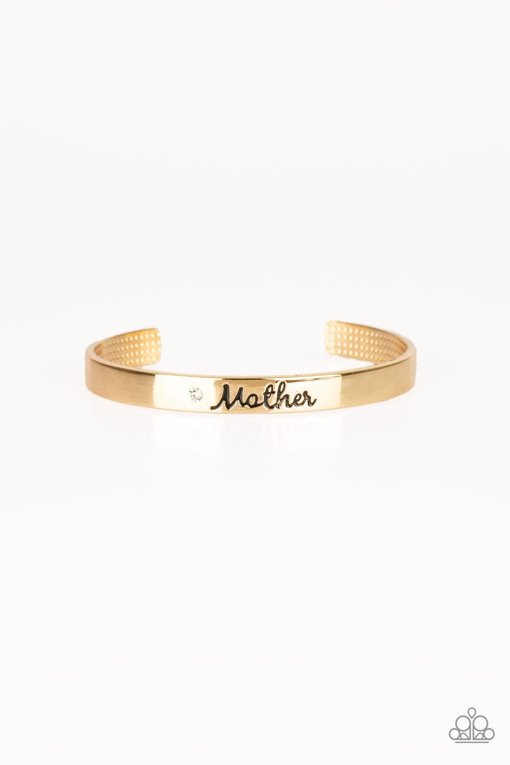 Paparazzi Accessories Every Day Is Mother’s Day - Gold A sleek gold cuff wraps around the wrist in a casual fashion. Dotted with a dainty white rhinestone, the shimmery cuff is engraved in the word “Mother” for a loving finish. Jewelry