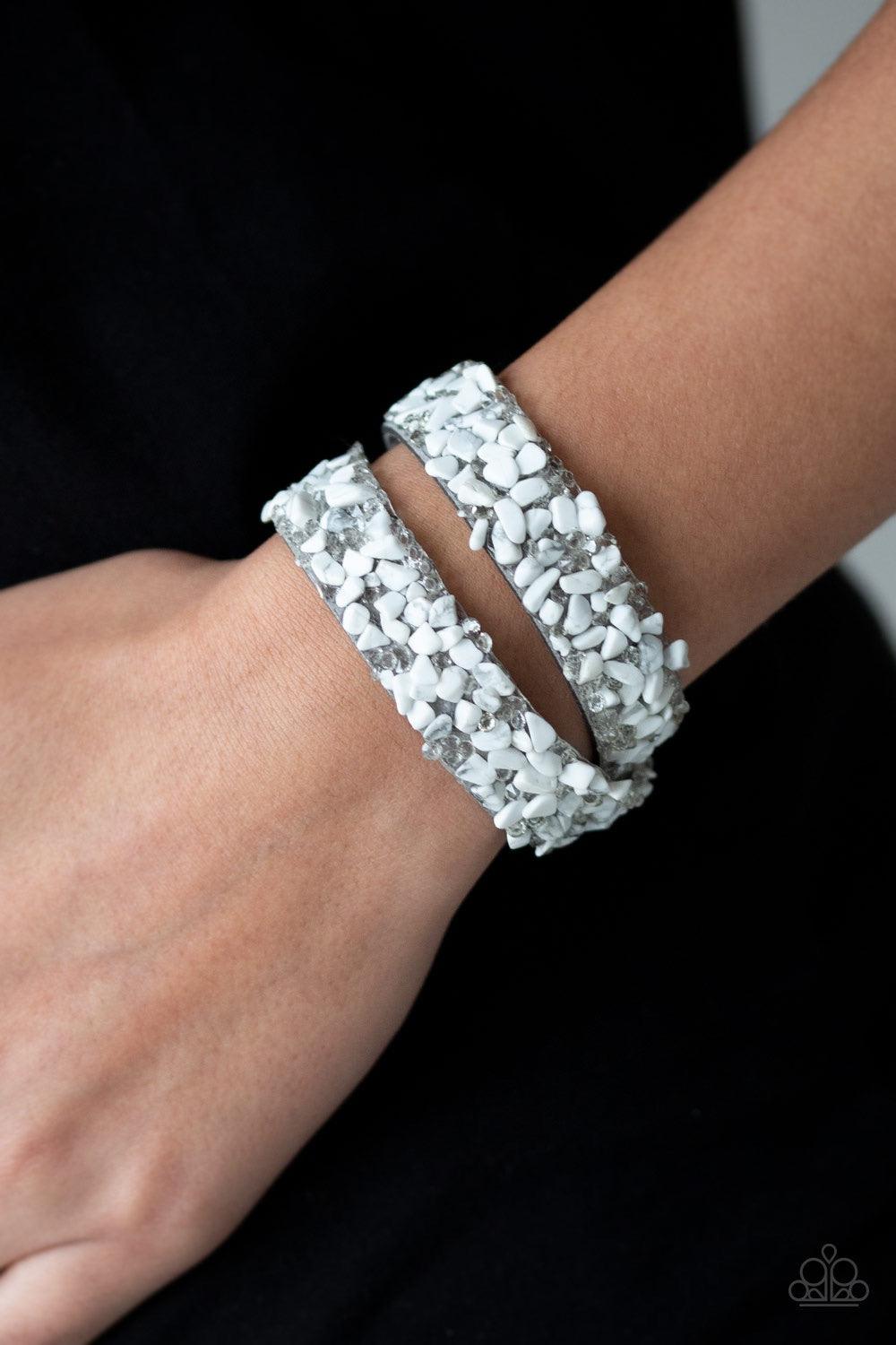 Paparazzi Accessories CRUSH to Conclusions - White A collection of crushed white rocks and glassy white rhinestone prisms are sprinkled across a gray suede band for a seasonal look. The elongated band allows for a trendy double wrap design. Features an ad