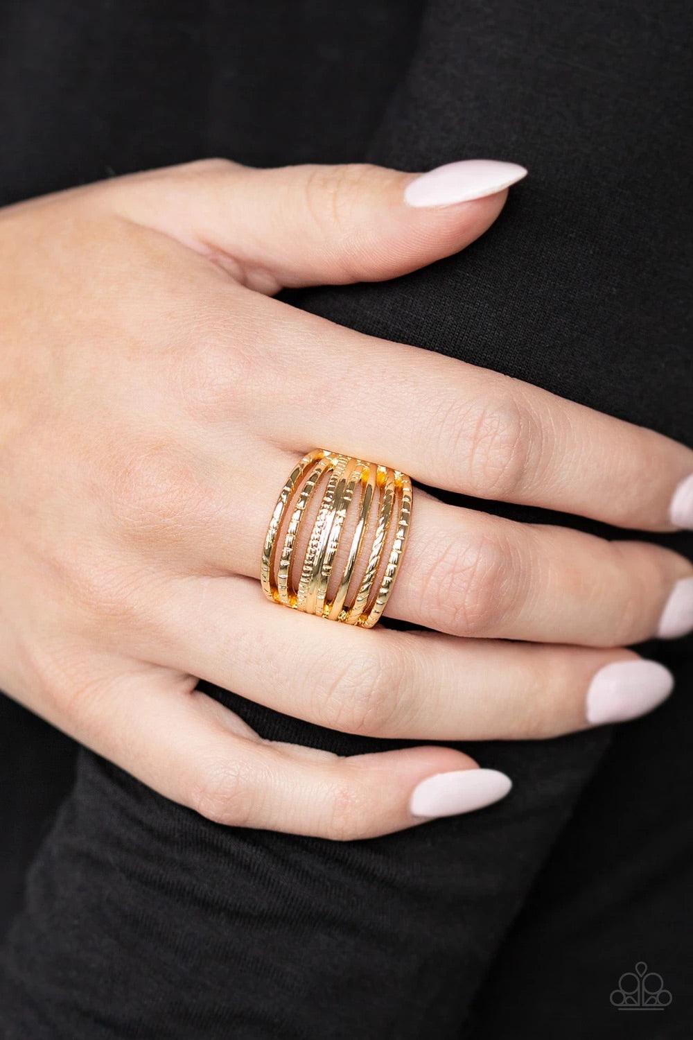 Paparazzi Accessories Basic Maverick - Gold A collection of smooth and textured gold bars arc across the finger, stacking into a thick layered band. Features a stretchy band for a flexible fit. Sold as one individual ring. Jewelry