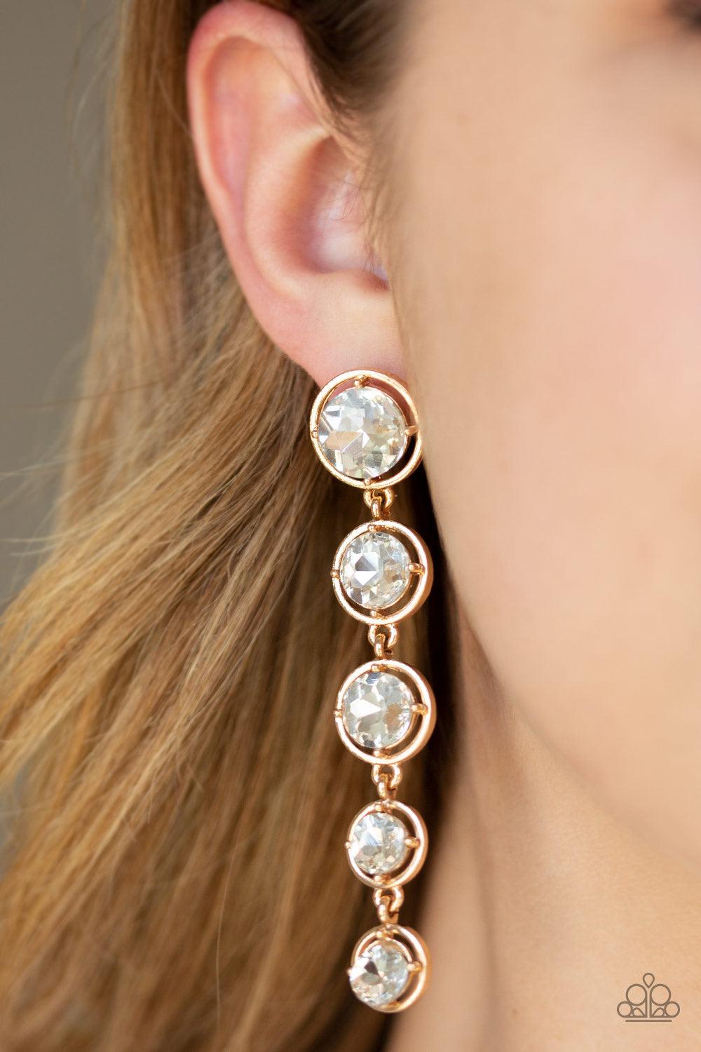 Paparazzi Accessories Drippin In Starlight - Gold Featuring sleek gold fittings, faceted white gems gradually decrease as they trickle from the ear for a glamorous look. Earring attaches to a standard post fitting. Jewelry