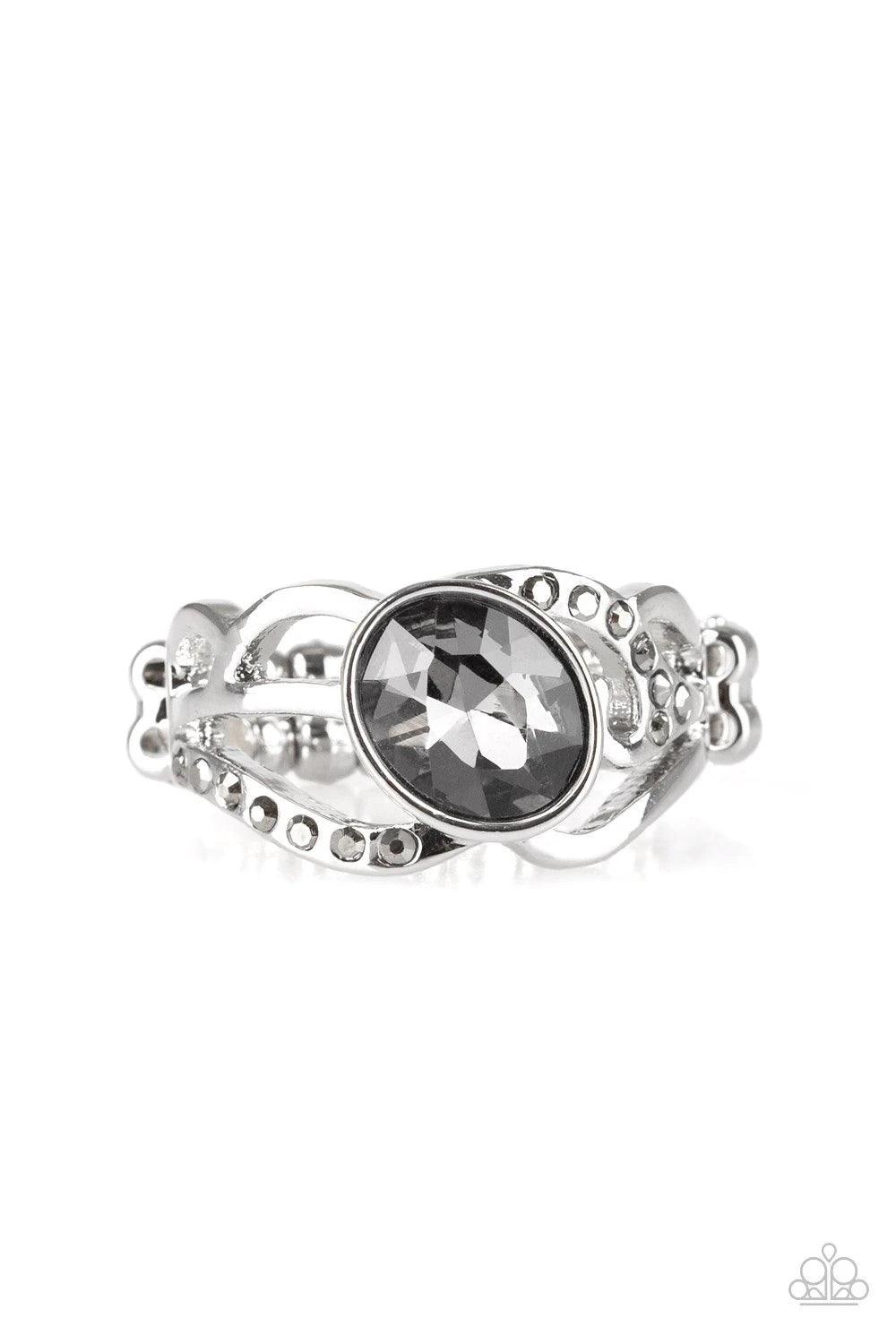 Paparazzi Accessories Couldn’t Care FLAWLESS - Silver Encrusted in sections of dainty hematite rhinestones, shimmery silver filigree curls around a smoky rhinestone center for a refined flair. Features a dainty stretchy band for a flexible fit. Sold as on