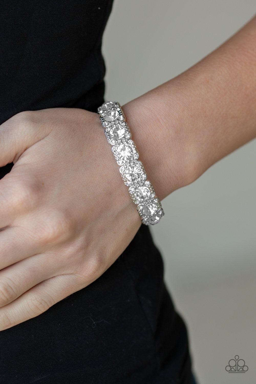 Paparazzi Accessories Blinged Out - White Featuring oversized white rhinestone centers, studded silver frames radiating in glassy white rhinestones are threaded along a stretchy band around the wrist for a glamorous fashion. Jewelry