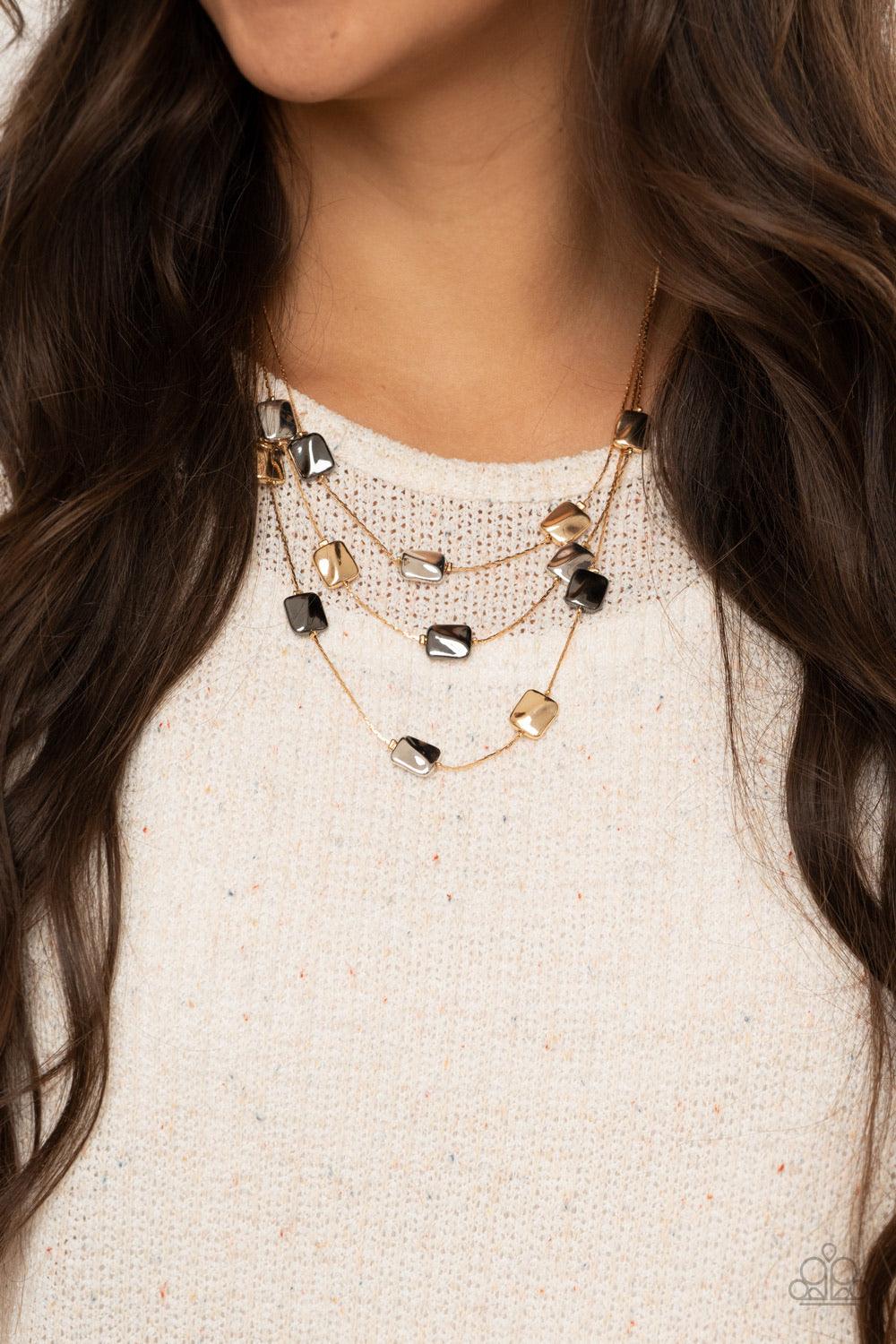 Paparazzi Accessories Downtown Reflections - Gold Featuring a decorative surface, dainty gold, gunmetal, and silver rectangular accents are fitted in place along three sleek gold chains, creating refined layers below the collar. Features an adjustable cla