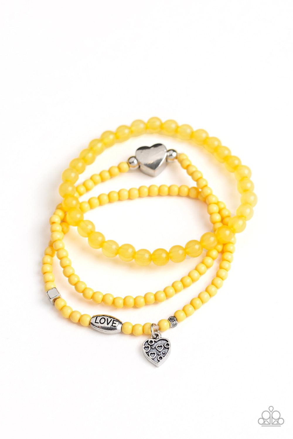 Paparazzi Accessories Really Romantic - Yellow An array of glassy and polished yellow beads are threaded along stretchy bands. Infused with silver accents, a collection of silver heart charms and a bead spelling out the word, "love", adorn the beaded stra