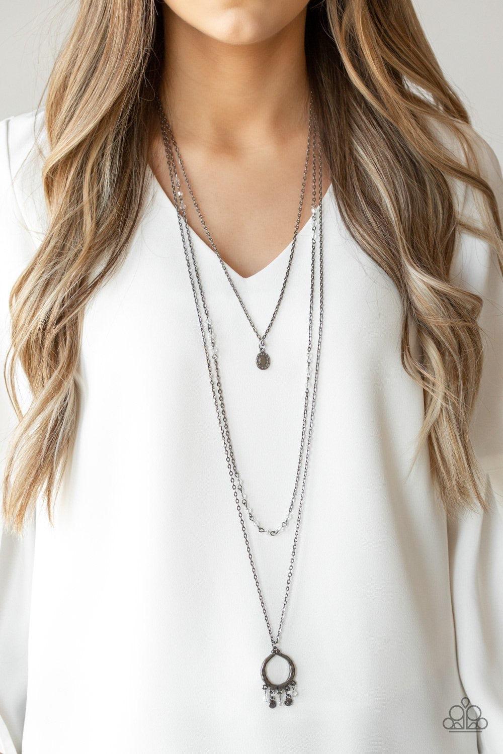 Paparazzi Accessories Treasures And Trinkets ~Black nfused with sporadic sections of dainty crystal-like beads, three dainty gunmetal chains layer down the chest. A dainty gunmetal frame swings from the uppermost chain, while a hammered pendant featuring