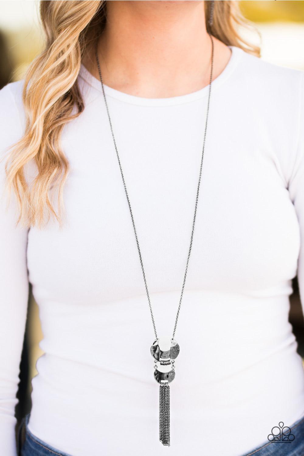Paparazzi Accessories Lunar Legend - Black Two delicately hammered frames link at the bottom of a shimmery gunmetal frame, creating a stacked pendant. Infused with dainty gunmetal rings, the crescent shaped frames give way to a shimmery chain fringe for a