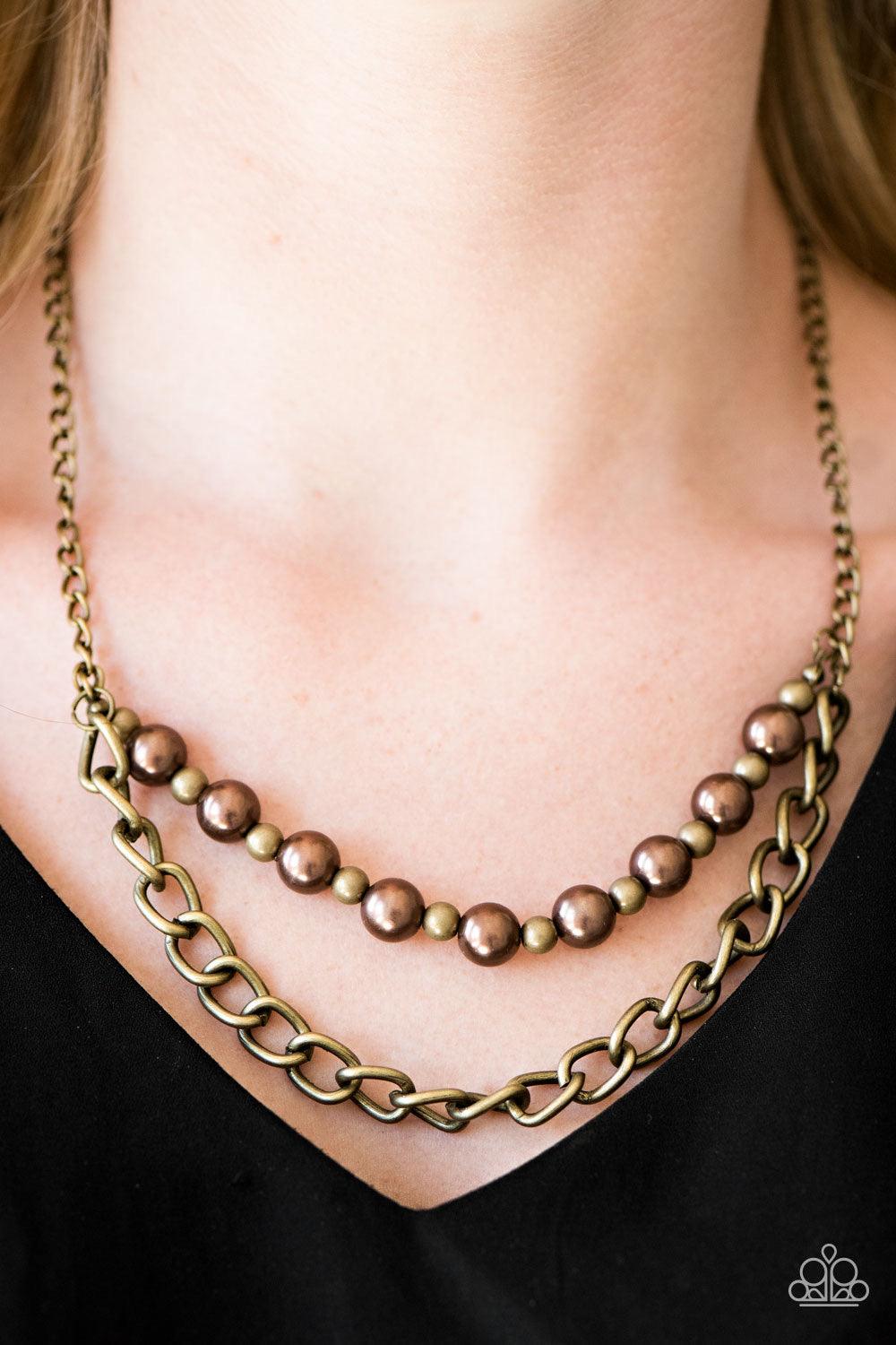Paparazzi Accessories Glam And Grind - Brass Pearly brown and rustic brass beads are threaded along a skinny wire. The pearly beading gives way to a bold strand of brass chain, creating edgy layers below the collar. Features an adjustable clasp closure. S