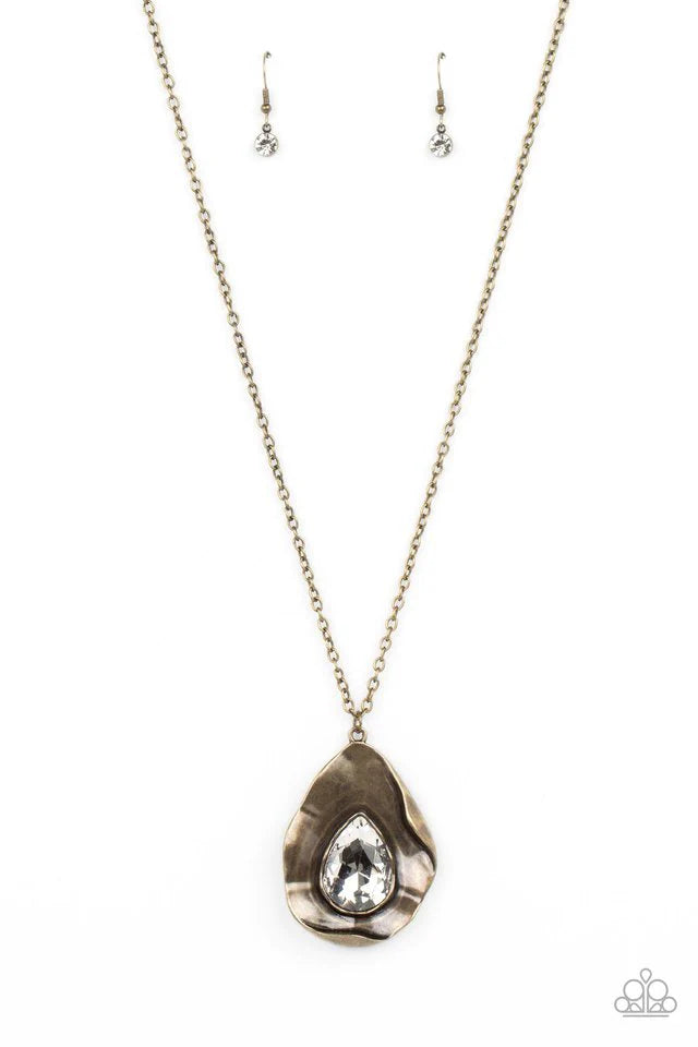 Paparazzi Accessories Surrealist Sparkle - Brass A warped brass frame gently folds around an oversized white teardrop gem center, resulting in a gritty yet glamorous pendant at the bottom of a lengthened brass chain. Features an adjustable clasp closure.