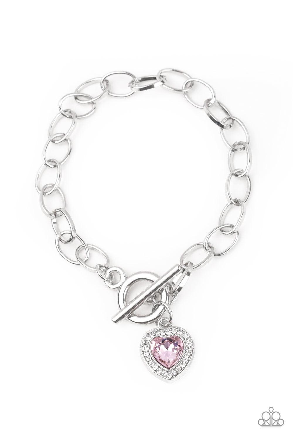 Paparazzi Accessories Going Steady - Pink Featuring a pink heart-shaped rhinestone center, a glittery white rhinestone encrusted silver frame swings from a shimmery silver chain for a flirtatious fashion. Features a toggle closure. Jewelry