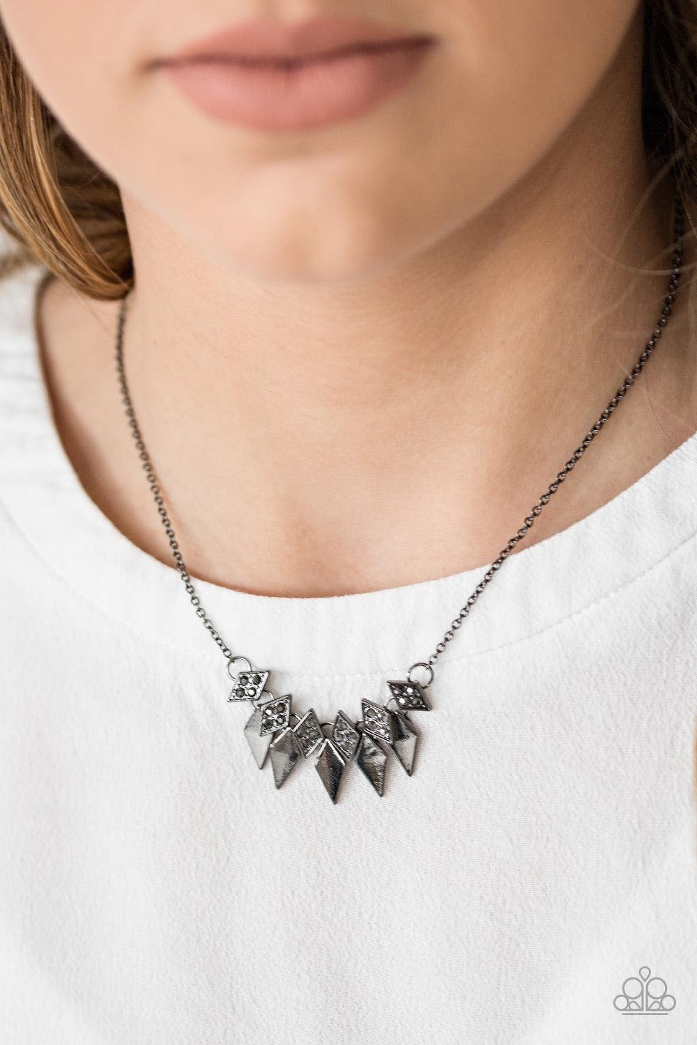 Paparazzi Accessories Over The Edge - Black Encrusted in glittery hematite rhinestones, dainty diamond-shaped frames give way to matching gunmetal frames, creating an edgy fringe below the collar. Features an adjustable clasp closure. Sold as one individu