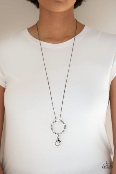 Paparazzi Accessories Center of Attention Lanyard - Black Encrusted in glittery white rhinestones, a dramatic gunmetal hoop swings from the bottom of a lengthened gunmetal chain for a refined look. A lobster clasp hangs from the bottom of the design to al