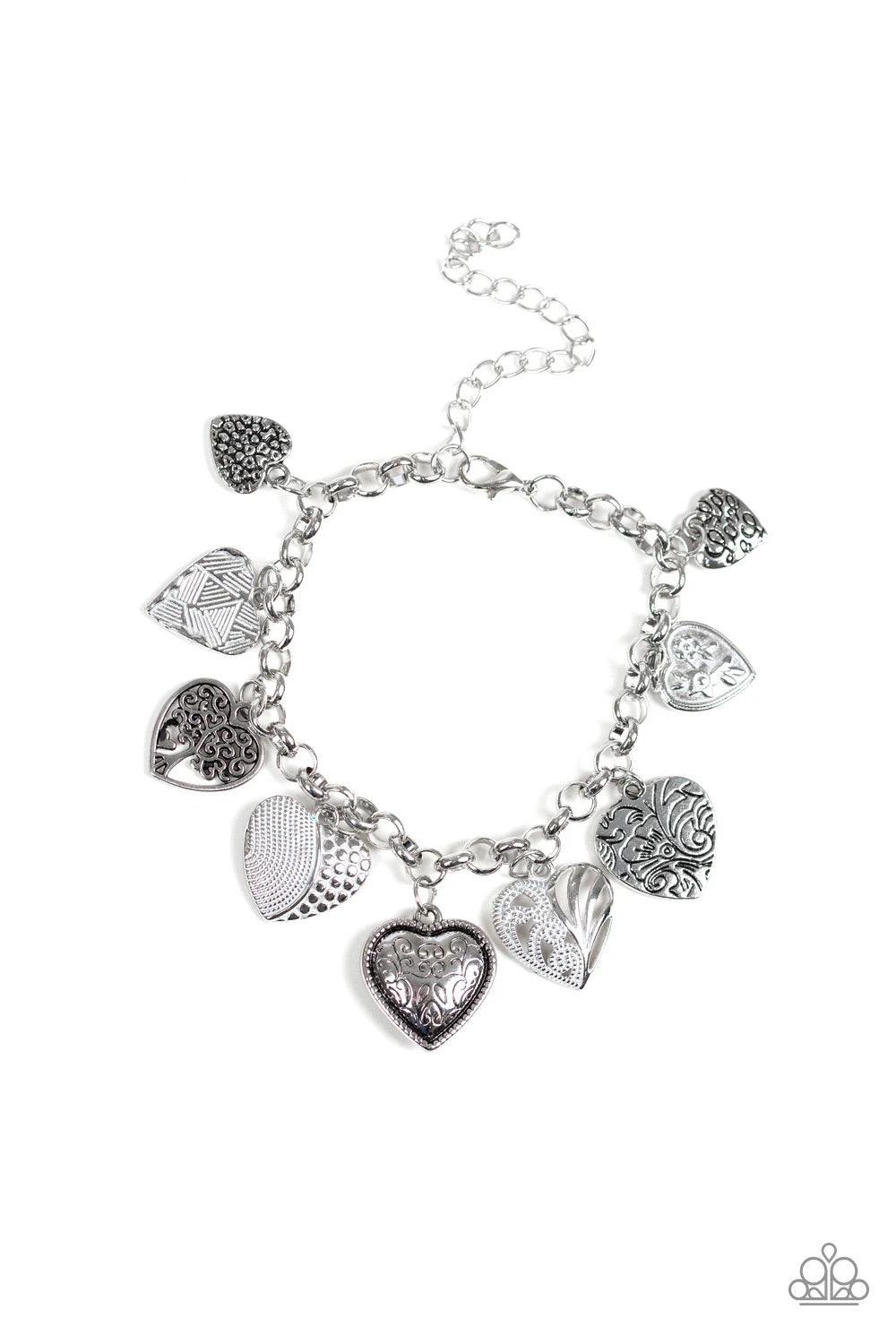 Paparazzi Accessories Garden Hearts - White Featuring an array of floral patterns, a collection of silver hearts swing from a shimmery silver chain. Alternating charms are brushed in a shiny white finish, creating a colorful fringe around the wrist. Featu